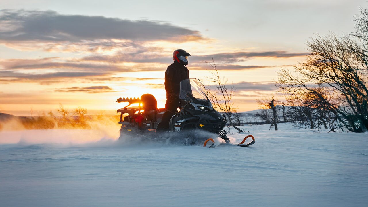 Man standing on his 2027 Lynx 59 Ranger PRO utility snowmobile at dawn