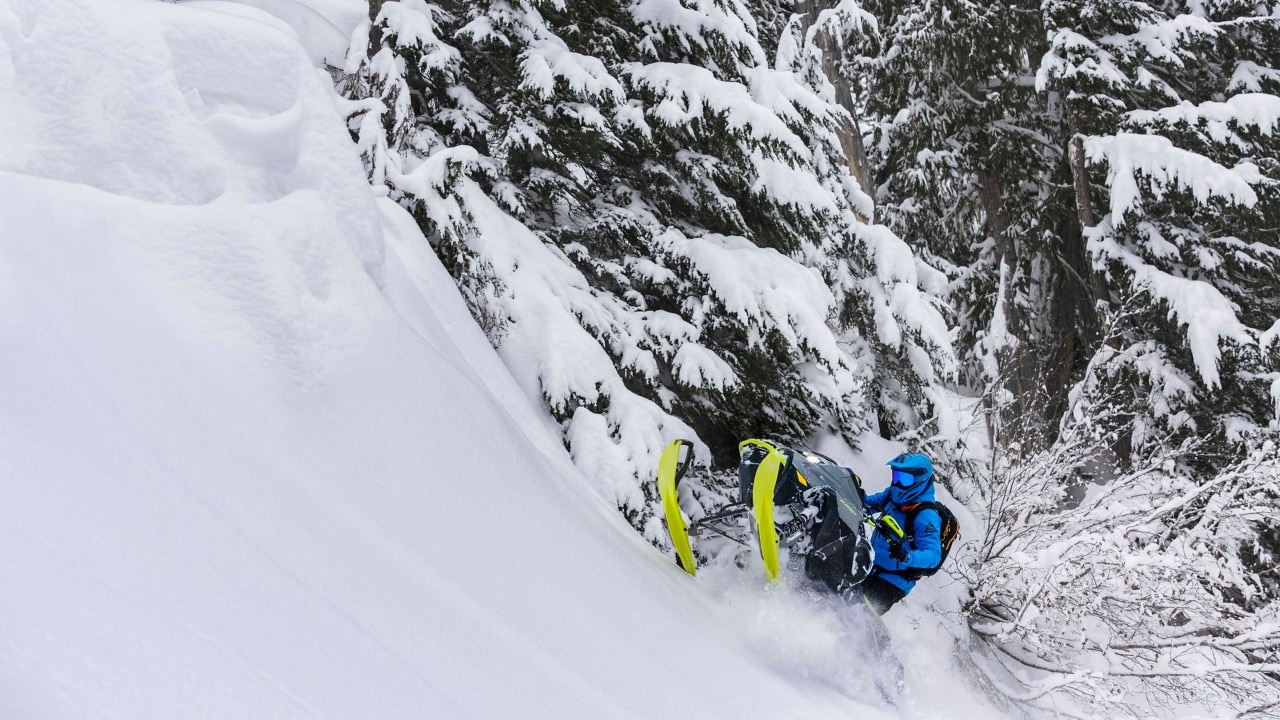 Mężczyzna jadący w głębokim śniegu na nowym skuterze śnieżnym Ski-Doo Summit 2023