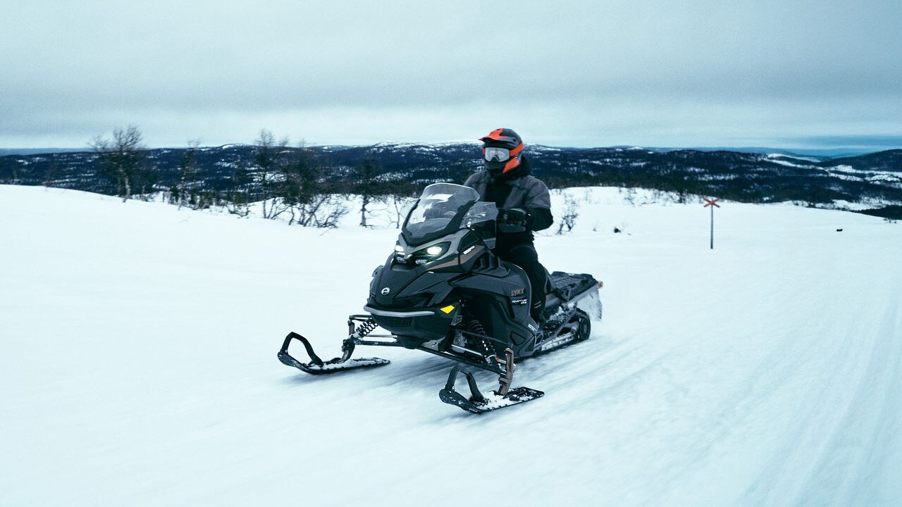 Man and woman riding together with Lynx Adventure Limited 2025 snowmobile with Passenger Kit