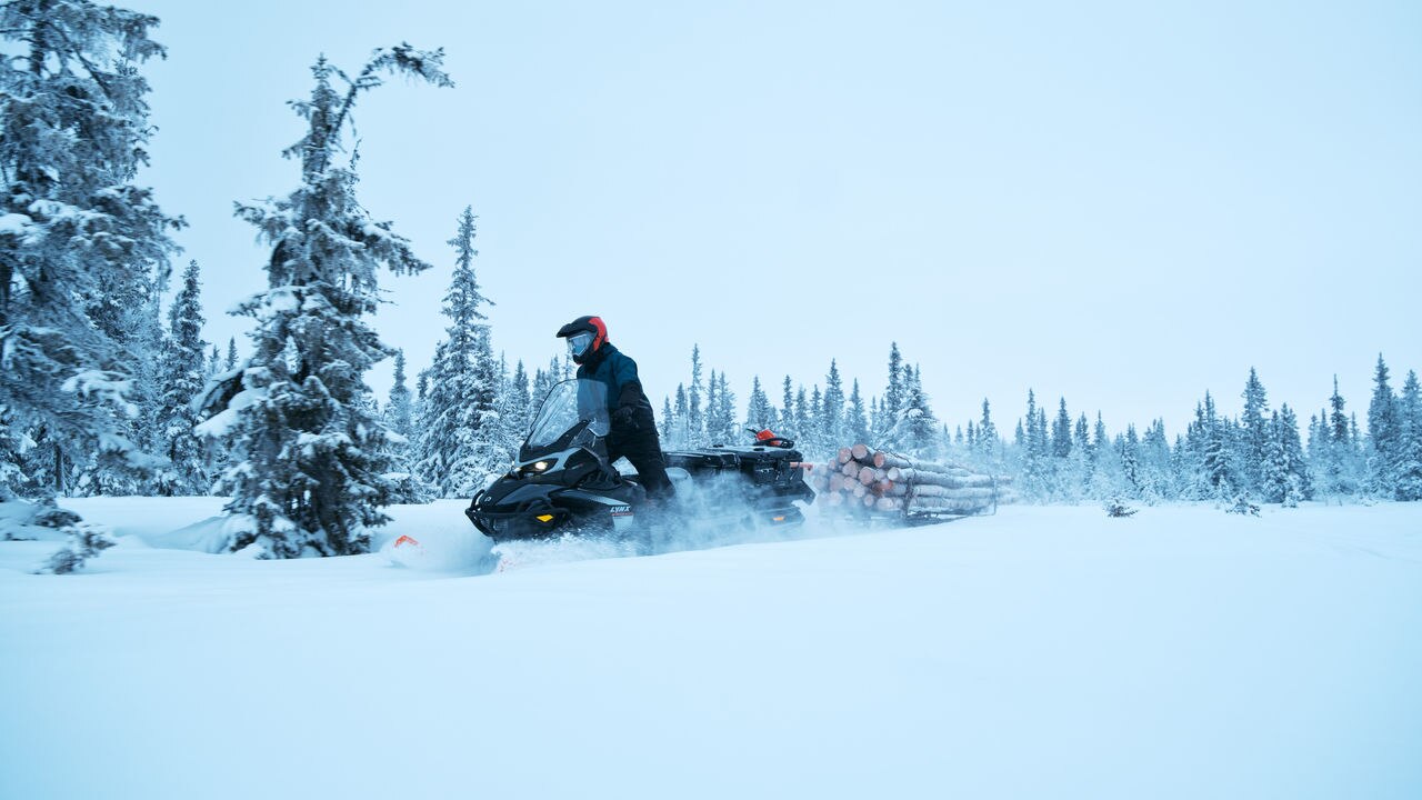 Rider pulling logs with a 2027 Lynx 69 Ranger PRO snowmobile