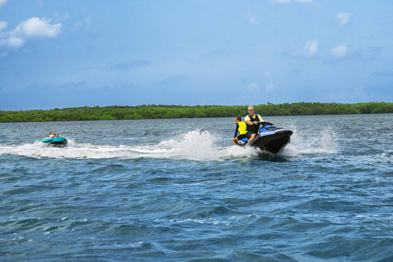 Dad and daughter on a Sea-Doo Spark 3UP personal watercraft pulling a tube