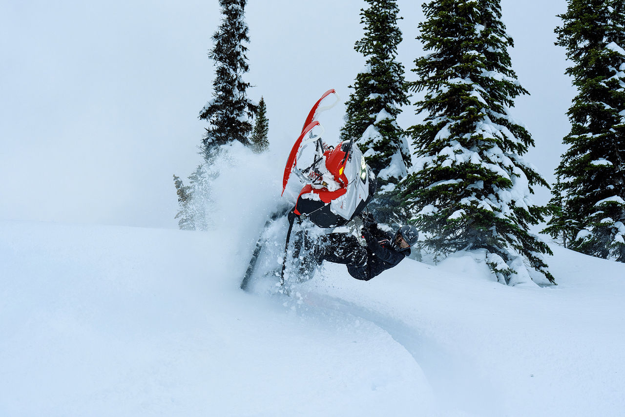 Rider performing a stunt with a 2027 Lynx Shredder RE snowmobile in deep snow