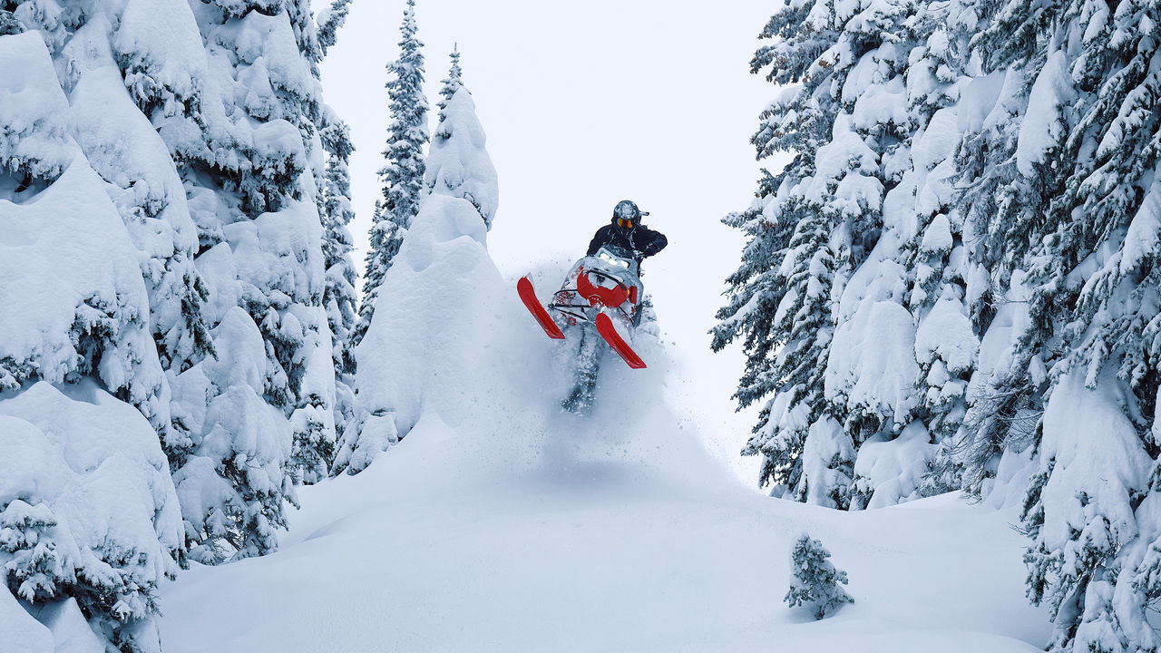 Rider performing jumping stunt between trees on a 2027 Lynx Shredder
