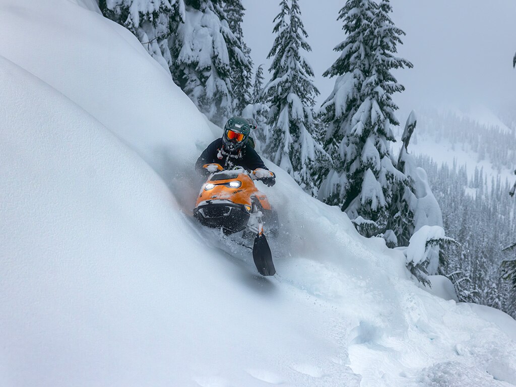 Rider riding up a snowy mountain on the 2027 Ski-Doo Summit