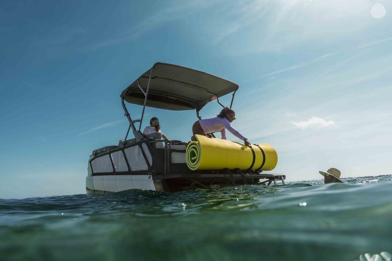 A family on a floating mattress near a 2026 Sea-Doo Switch Cruise on a lake
