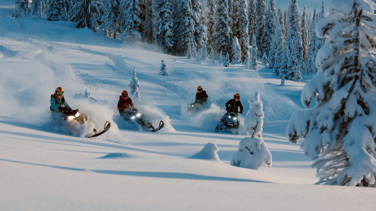 Four snowmobile riders riding in deep snow