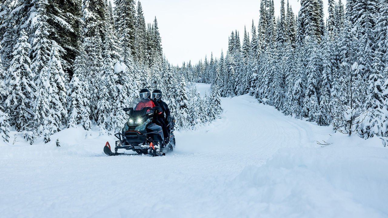 Двое едут на снегоходе Ski-Doo Expedition SE 2026 по заснеженному лесу