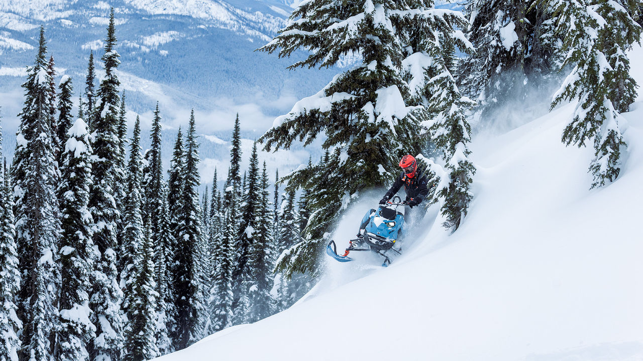 Райдер едет на снегоходе Ski-Doo Freeride 2026 по глубокому снегу в горах.