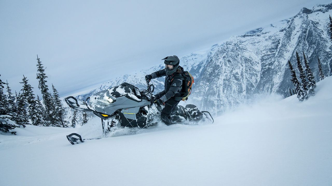 Райдер едет на снегоходе Ski-Doo Adrenaline 2026 с пакетом Edge по глубокому снегу в горах.