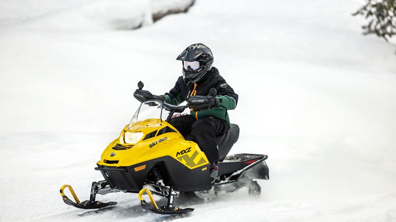 Подросток едет на молодежном снегоходе Ski-Doo MXZ 200
