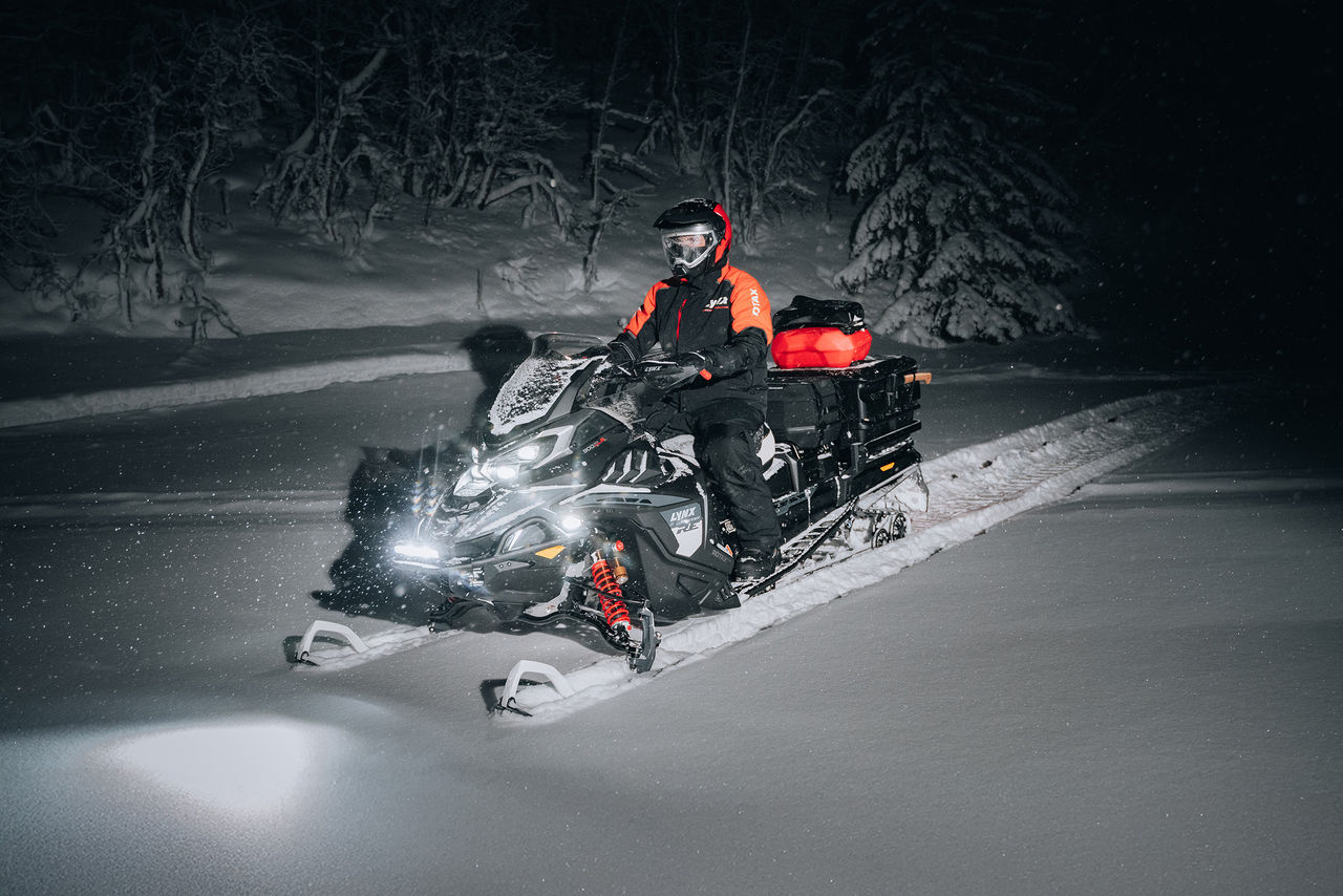 Rider riding 2027 Lynx Commander RE at night with cargo