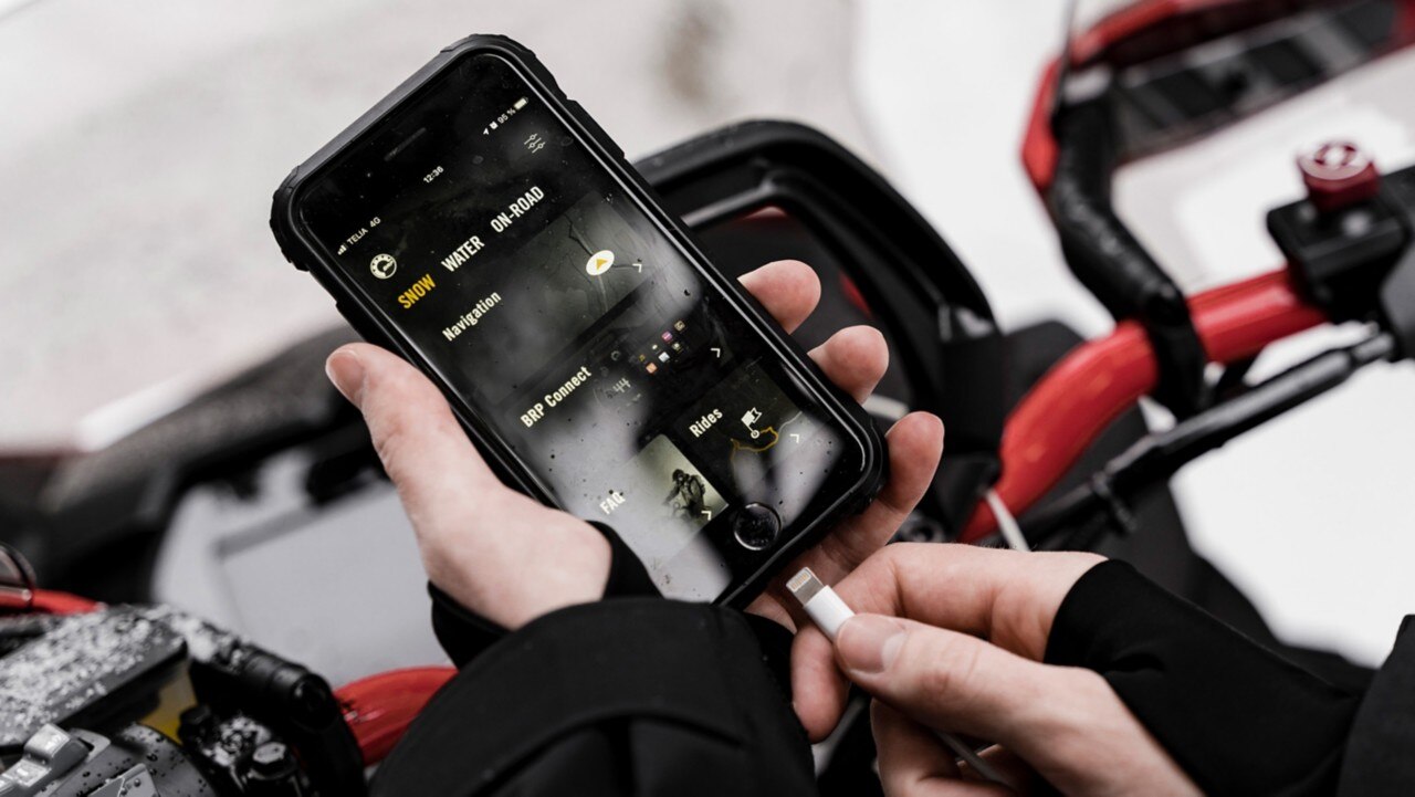 BRP GO! app on a phone near a Lynx snowmobile