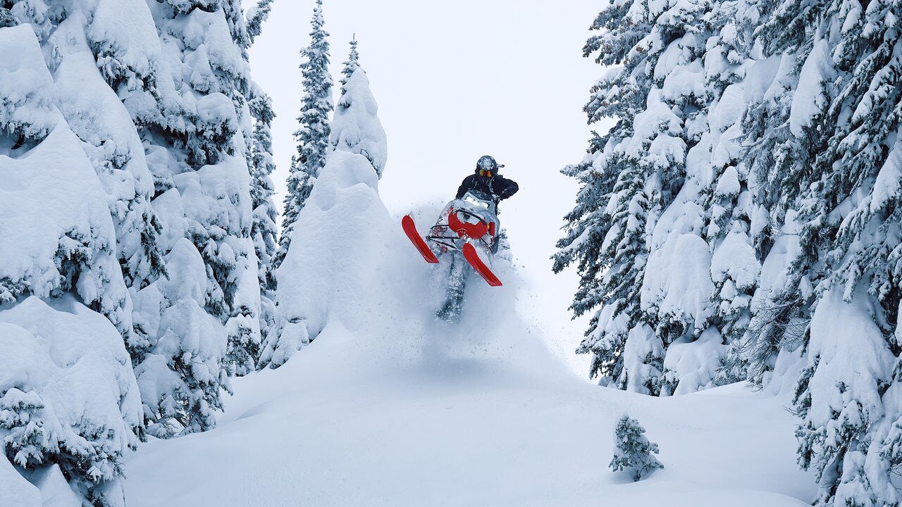 Rider performing jumping stunt between trees on a 2027 Lynx Shredder