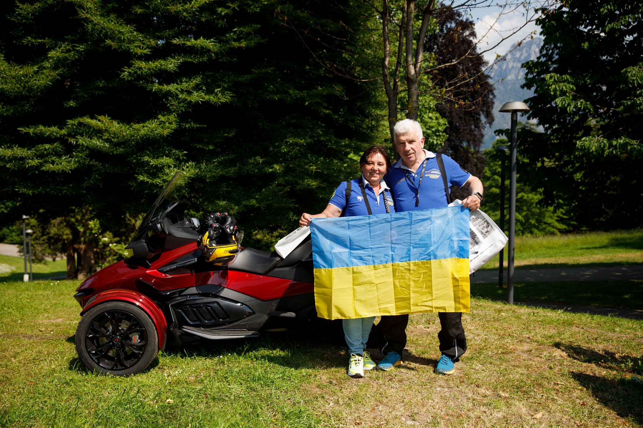 A smiling couple standing next to their 3-wheel