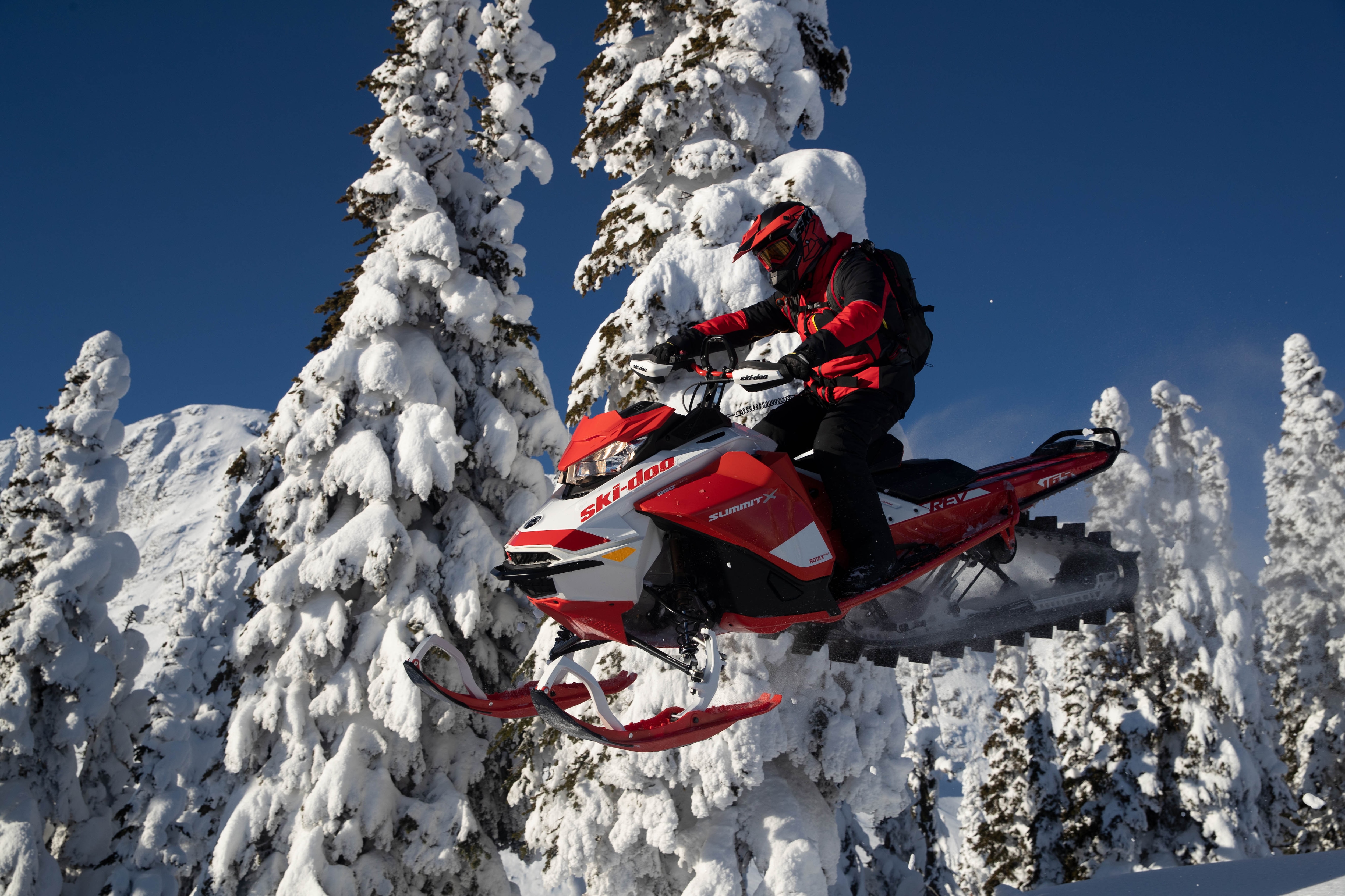 Mann fährt einen Ski-Doo Motorschlitten und fliegt durch die Luft