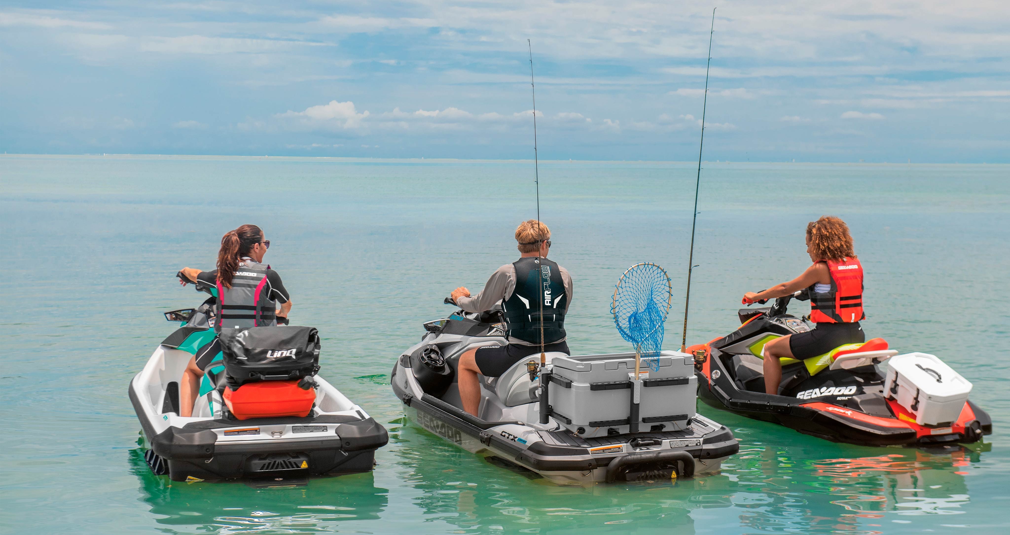 Traja kamaráti s rybárskym náčiním jazdia na svojom vodnom skútri Sea-Doo.