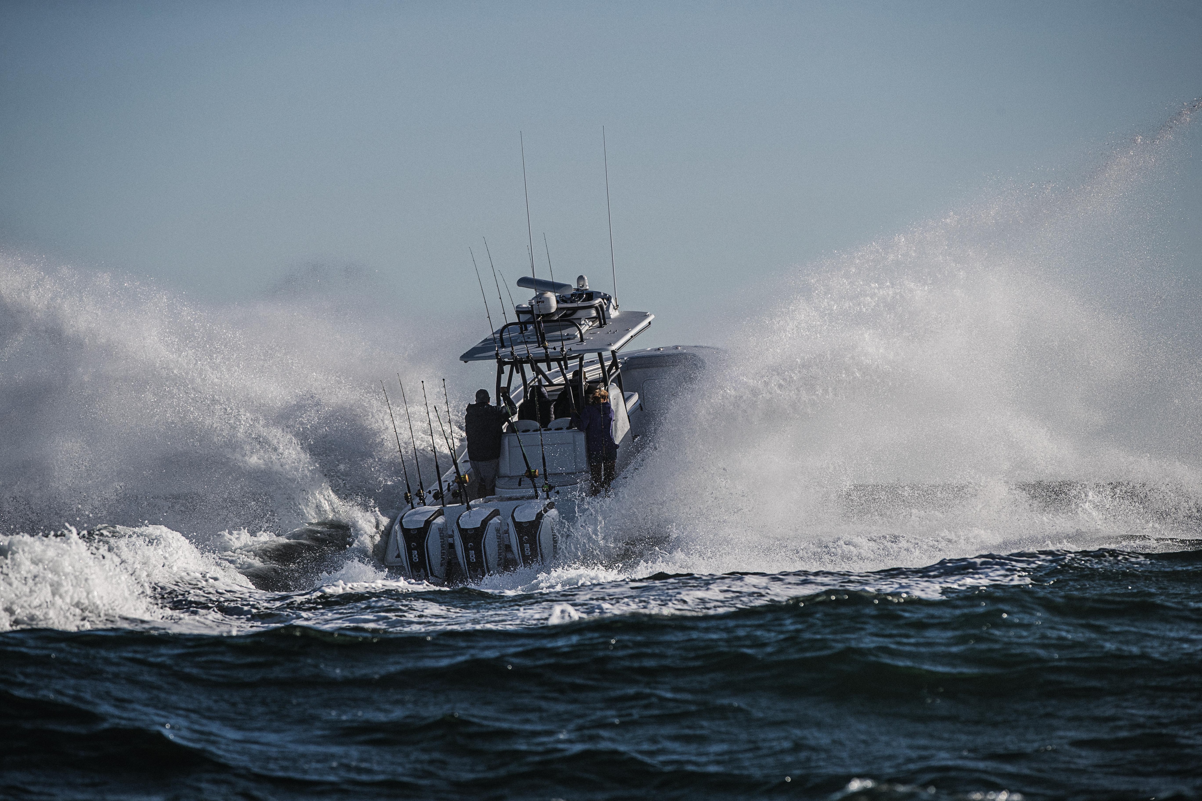 Boat yielding a triple Evinrude motor accelerating through water