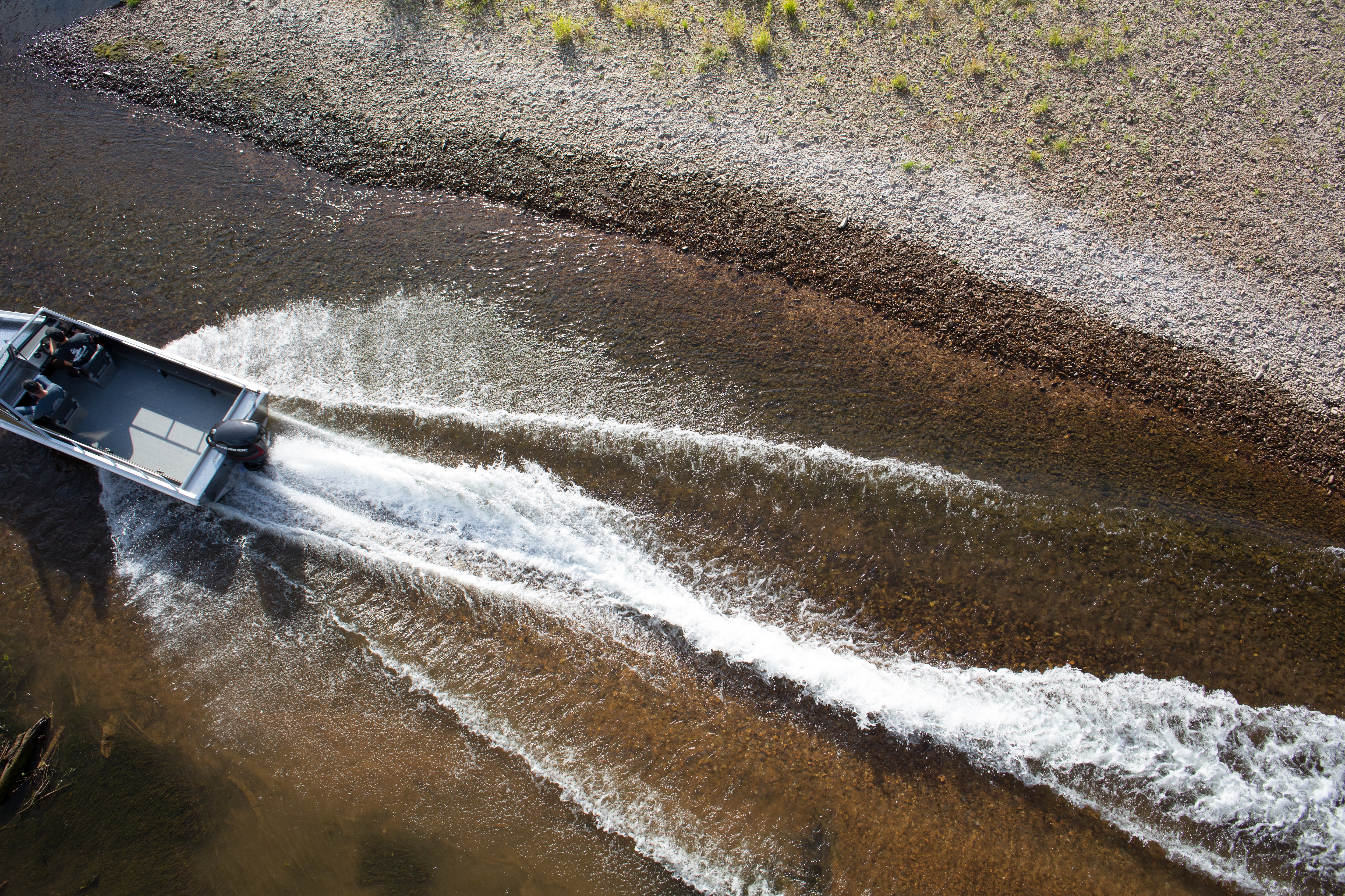 Two men driving a motorboat in shallow water 