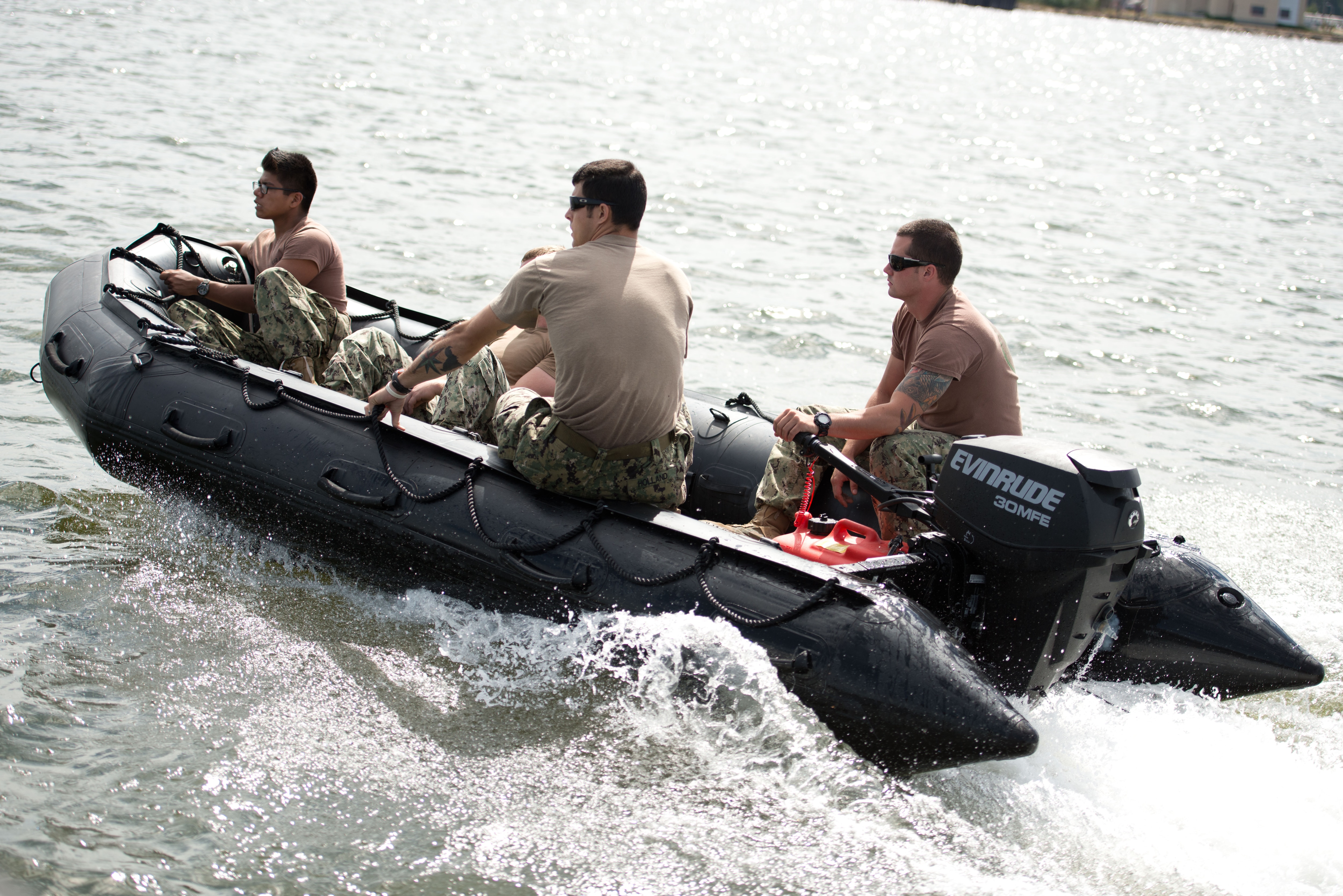 Military personnel driving a boat yielding an Evinrude motor