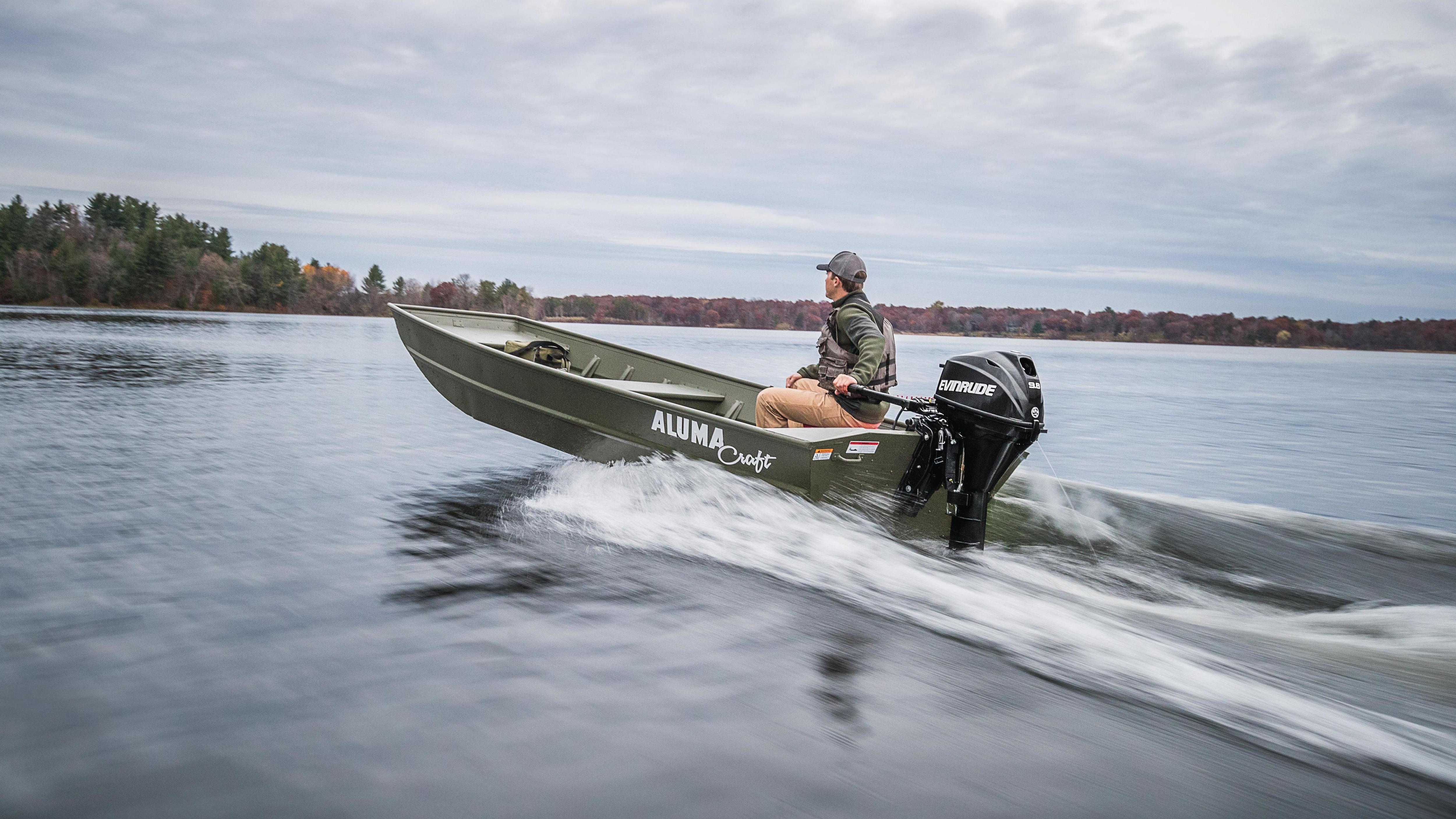 Man using his portable Evinrude motor to move his boat across a lake