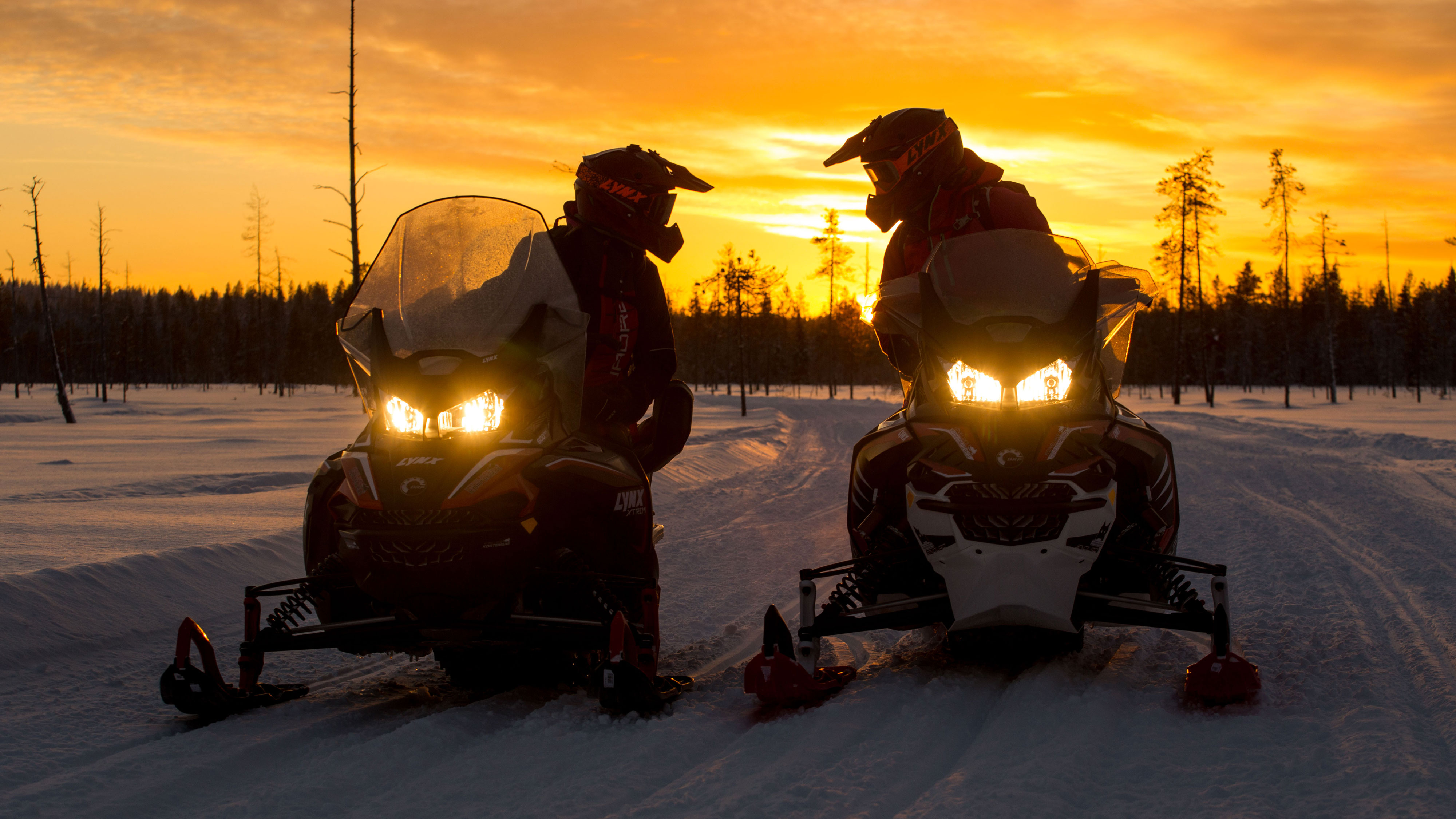 Minttu and Inari on Lynx snowmobile at sunset