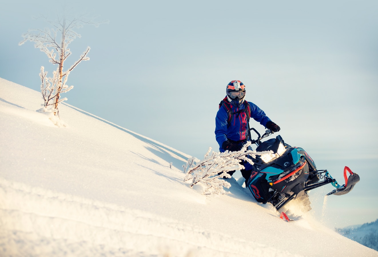 Muž jedoucí na po zasněženém kopci sněžném skútru Lynx BoonDocker 3900 