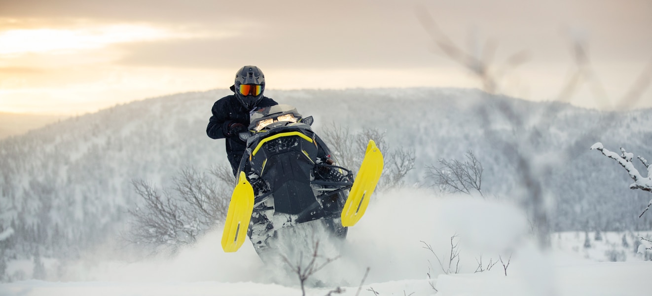 Čovjek skače sa svojim modelom motornih sanki Lynx Xtrim na vrh snježnog brda