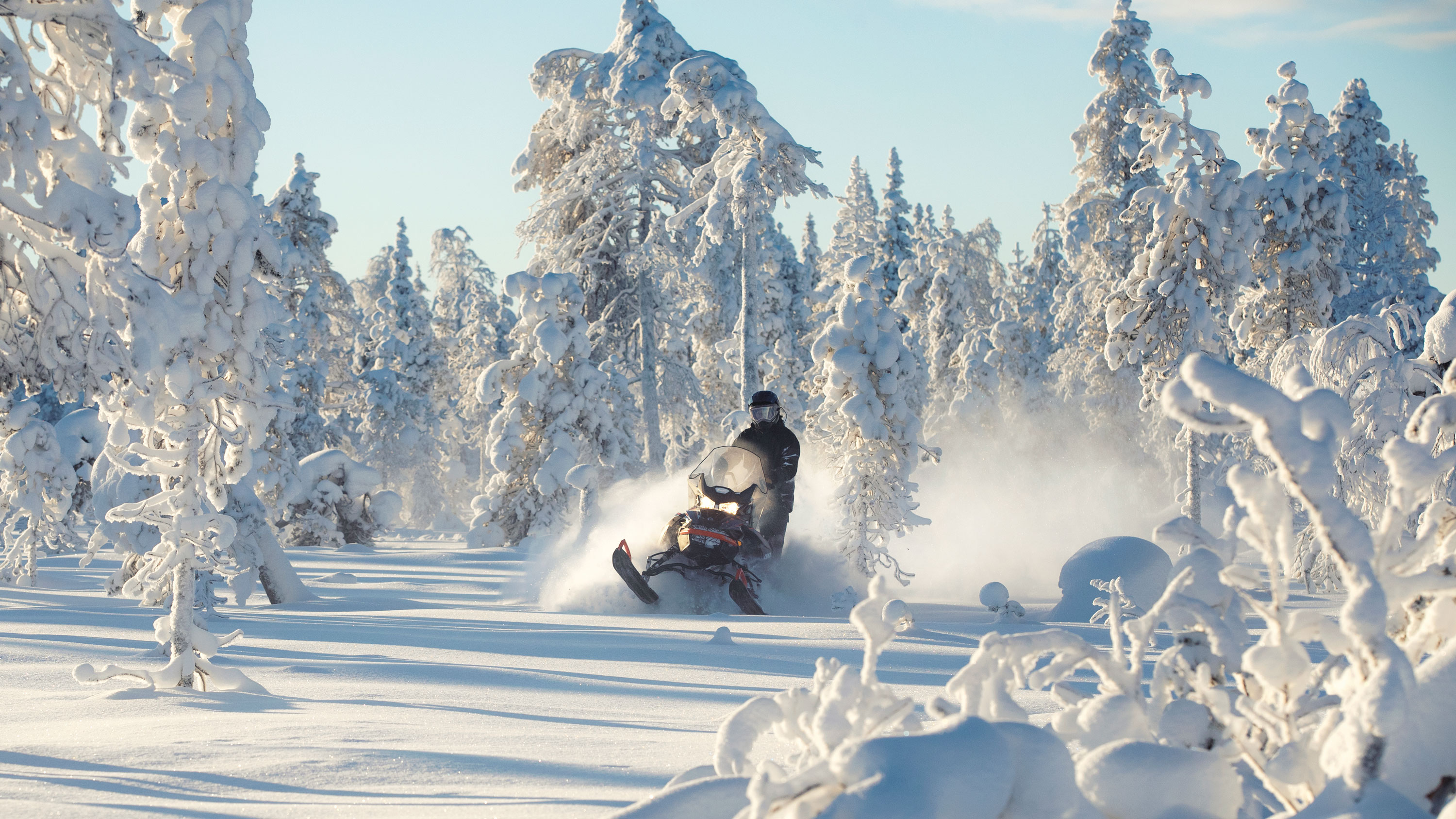 Muž jazdí na svojom snežnom skútri 2021 Lynx Commander do zasneženého lesa.
