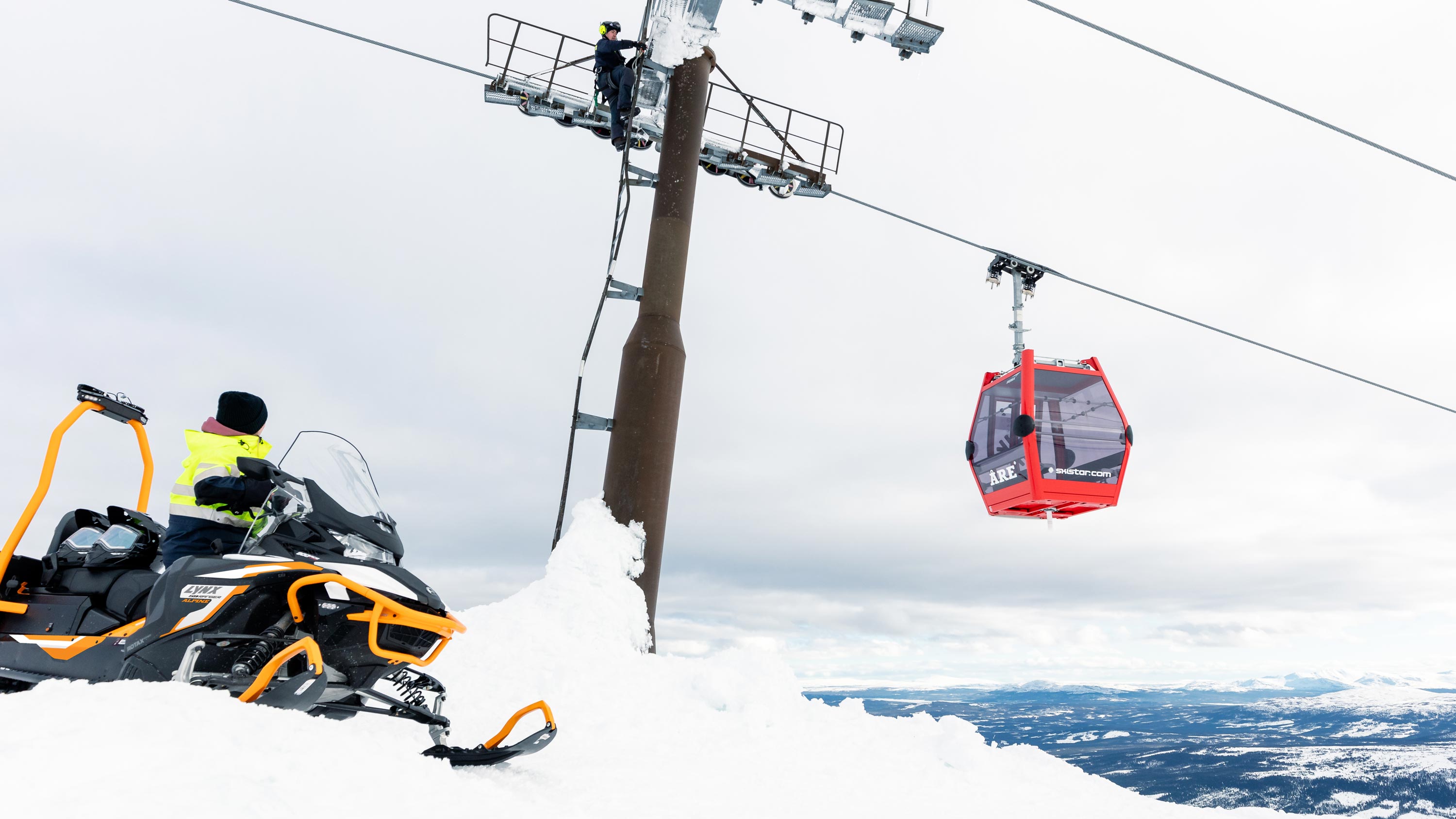 Lynx 59 Ranger snowmobile and a person fixing a ski lift