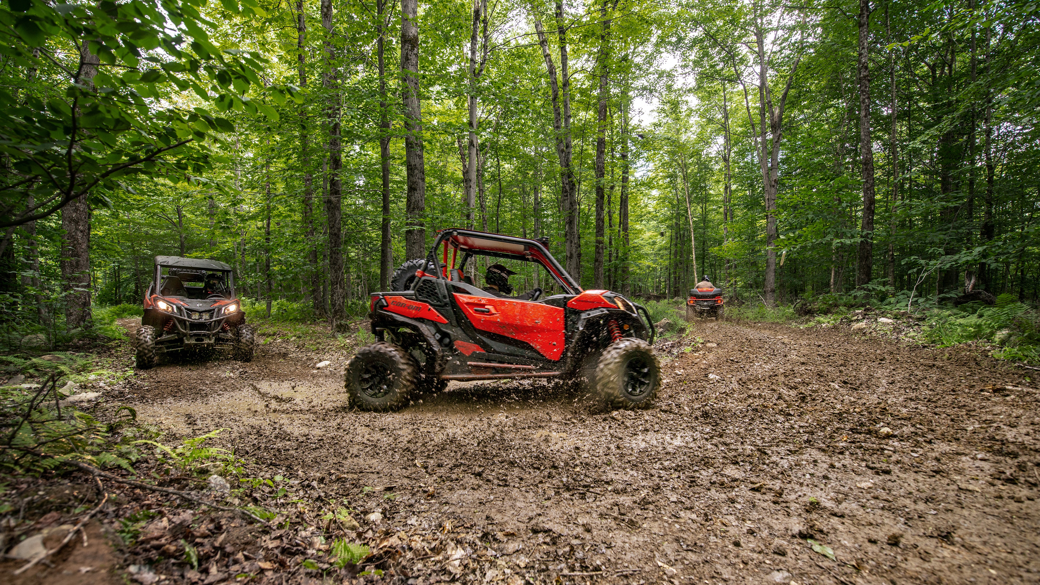 Group of friends driving their Maverick side-by-side in a forest