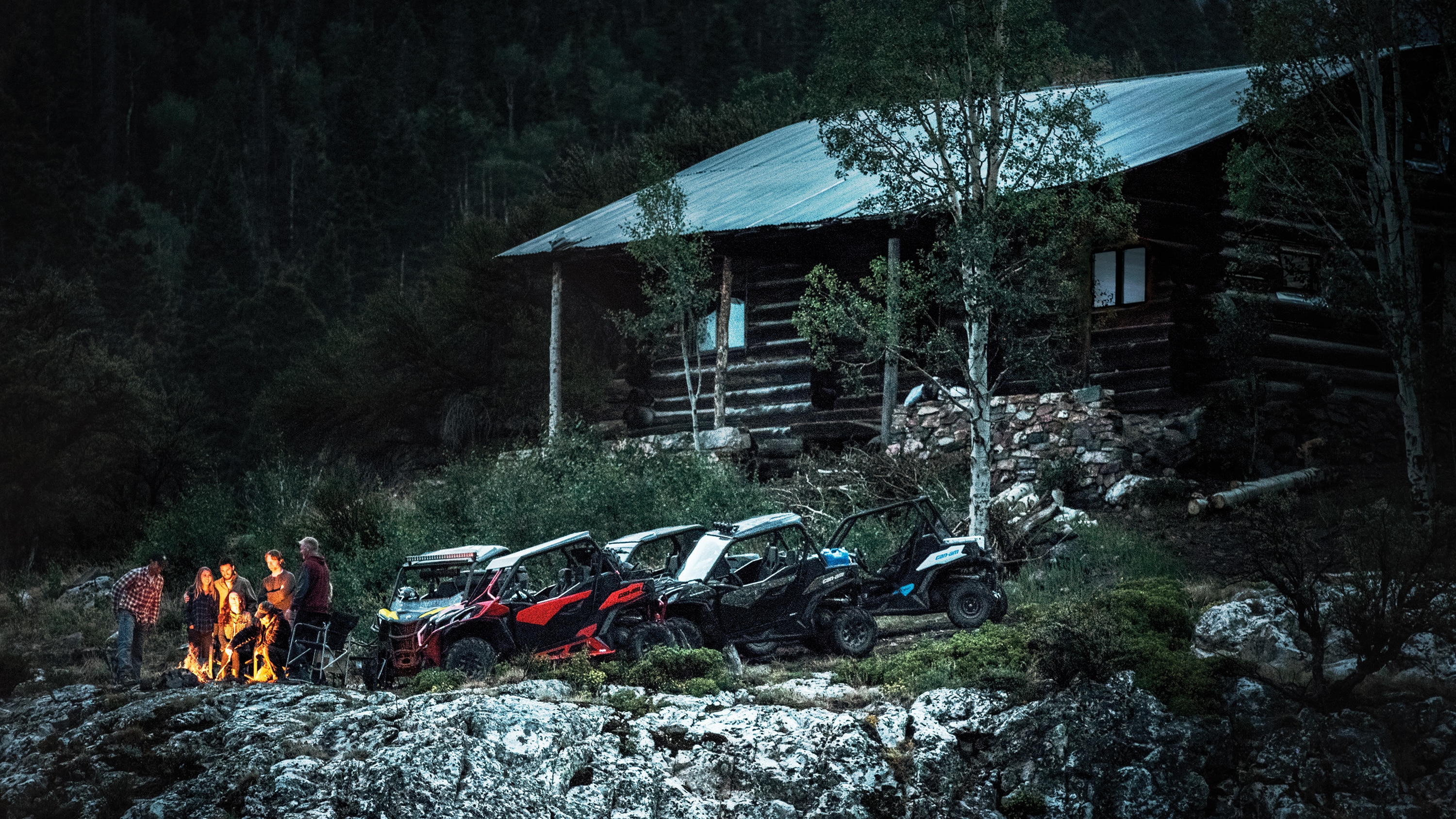 Friends near their Maverick Trail models close to a cabin in the woods