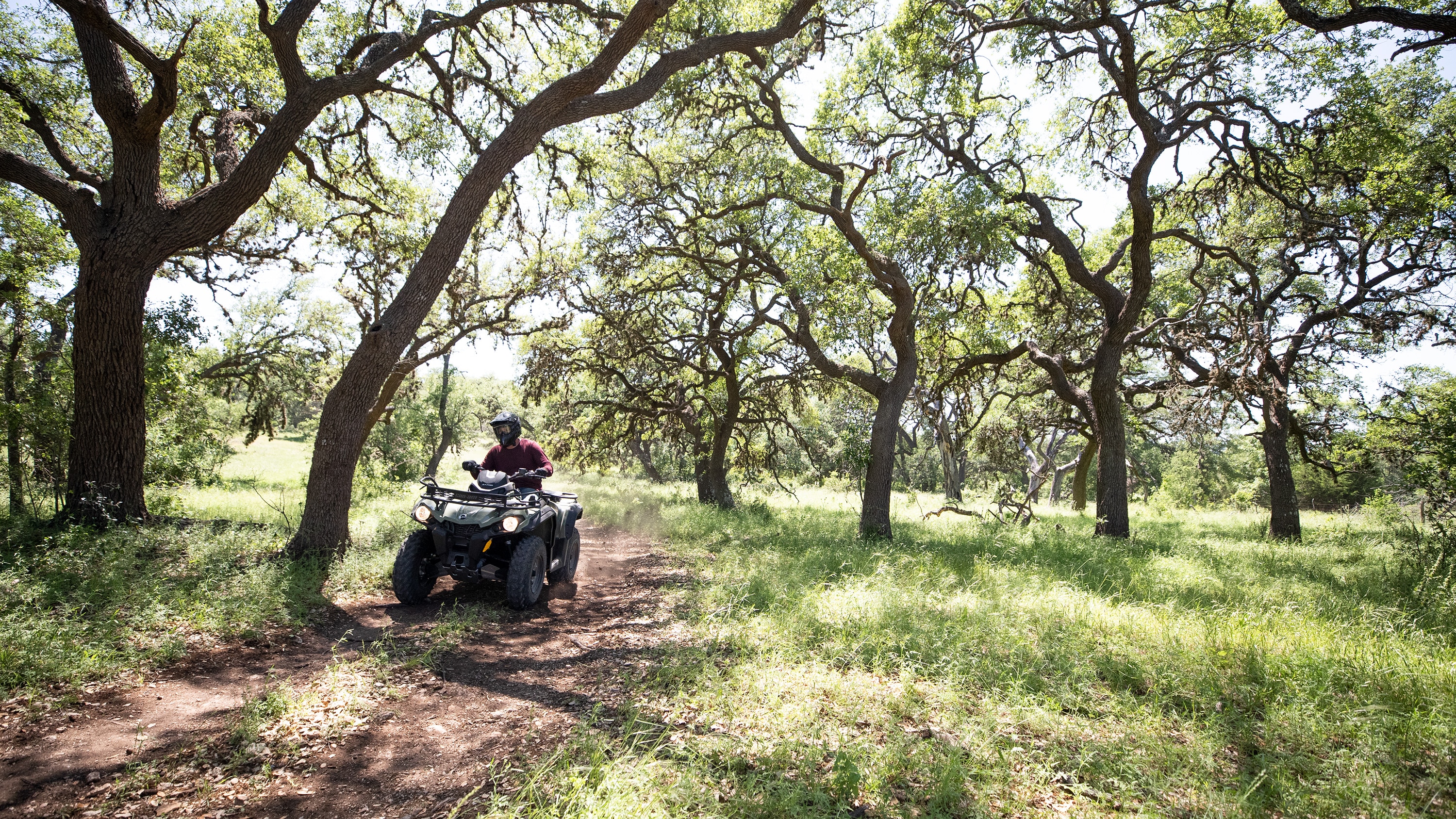 Muž jedoucí na čtyřkolce Outlander 450 lesem