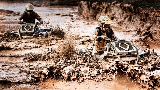 Two men driving their Outlander ATV through deep mud