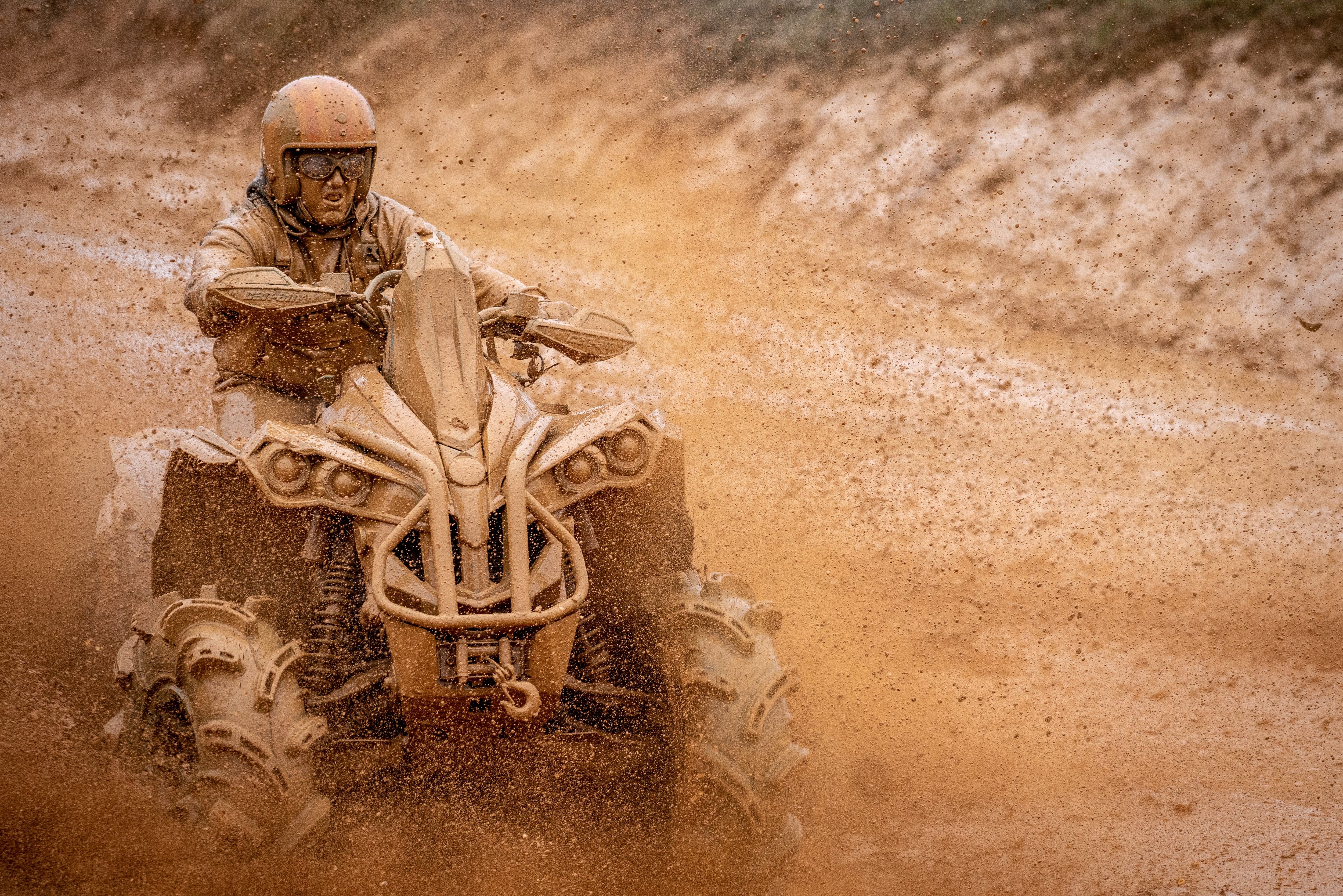 Man covered in mud is driving his Renegade ATV on a muddy trail