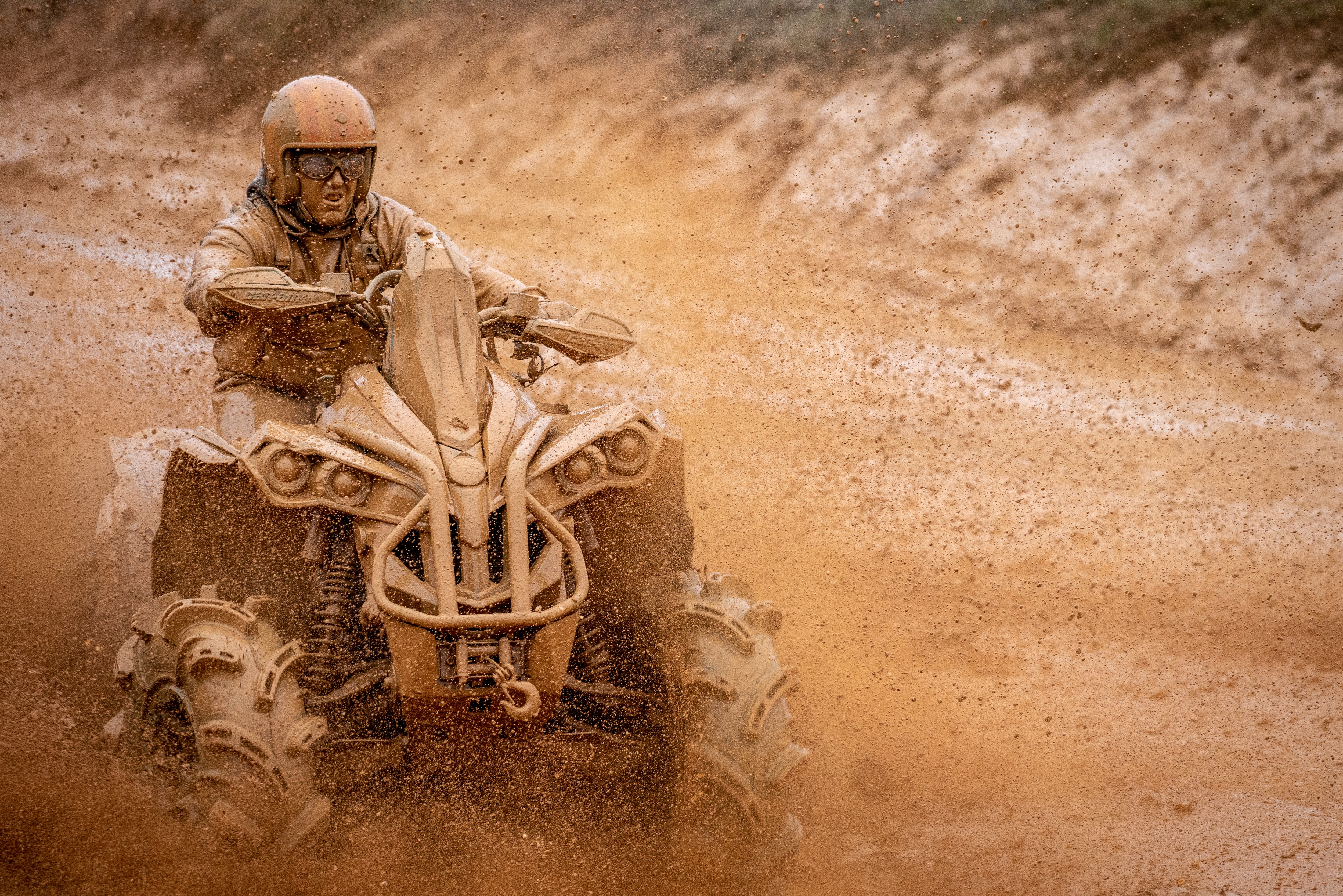 Zablácený muž jedoucí na čtyřkolce Renegade ATV blátivou cestou