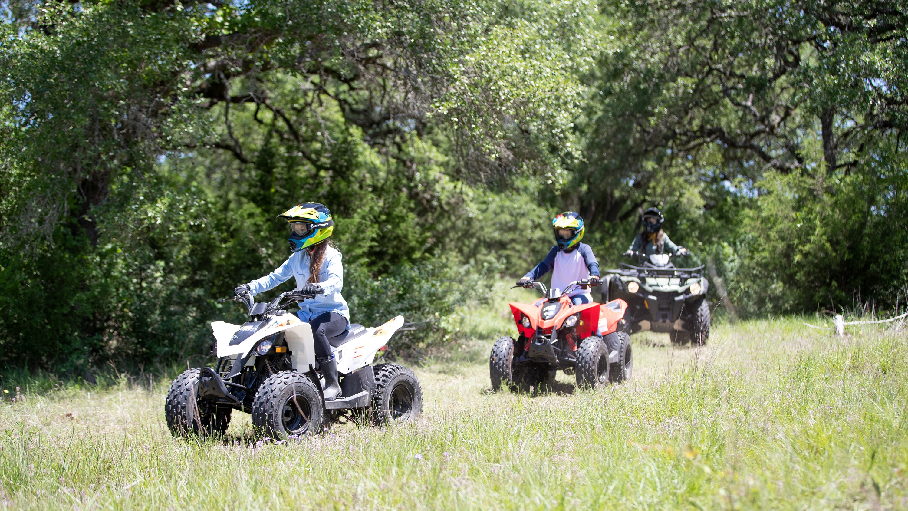 Pair of young kids driving a Can-Am DS in a forest trail