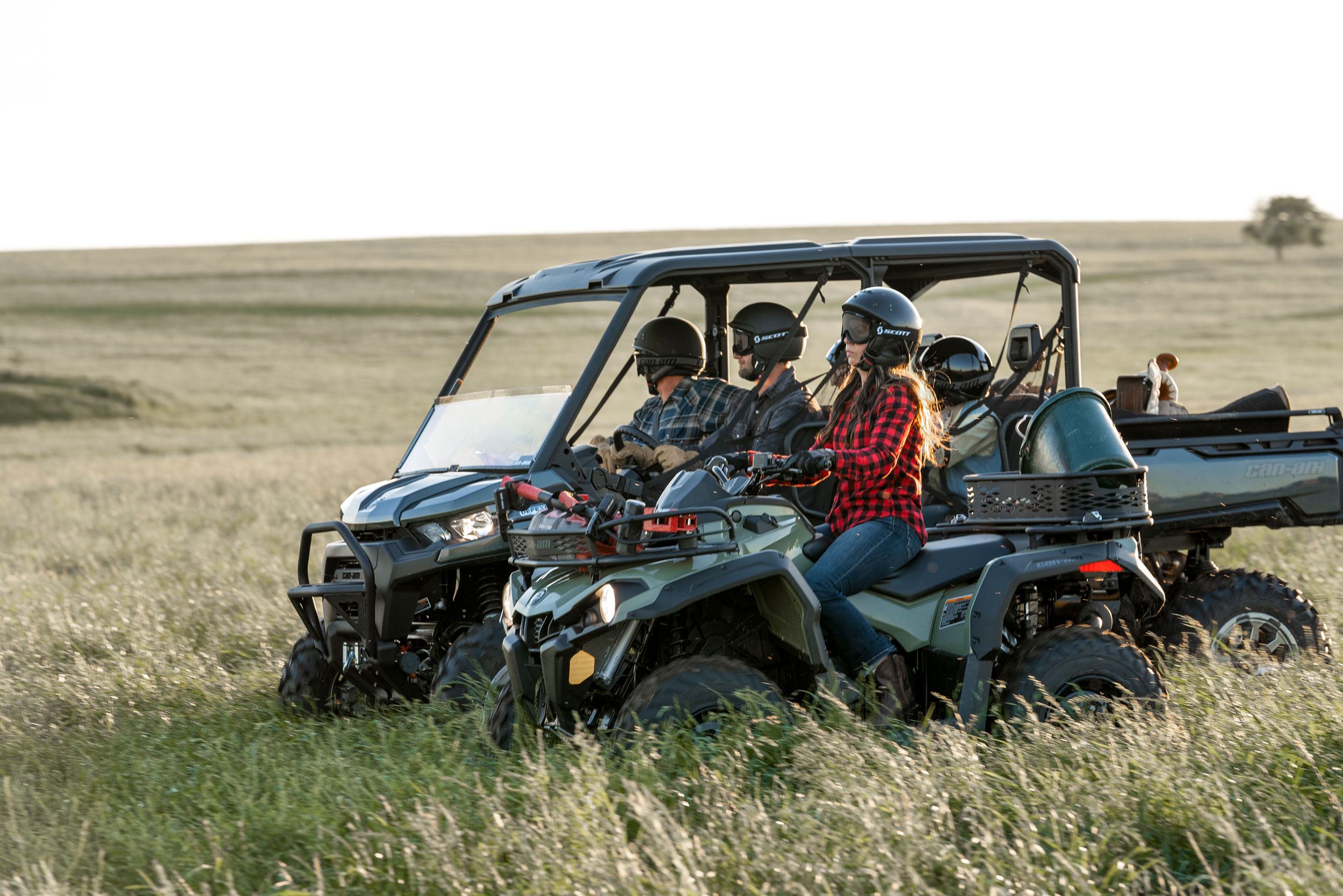 People riding a Can-Am Defender MAX Lonestar Edition side-by-side and a Can-Am Outlander DPS ATV