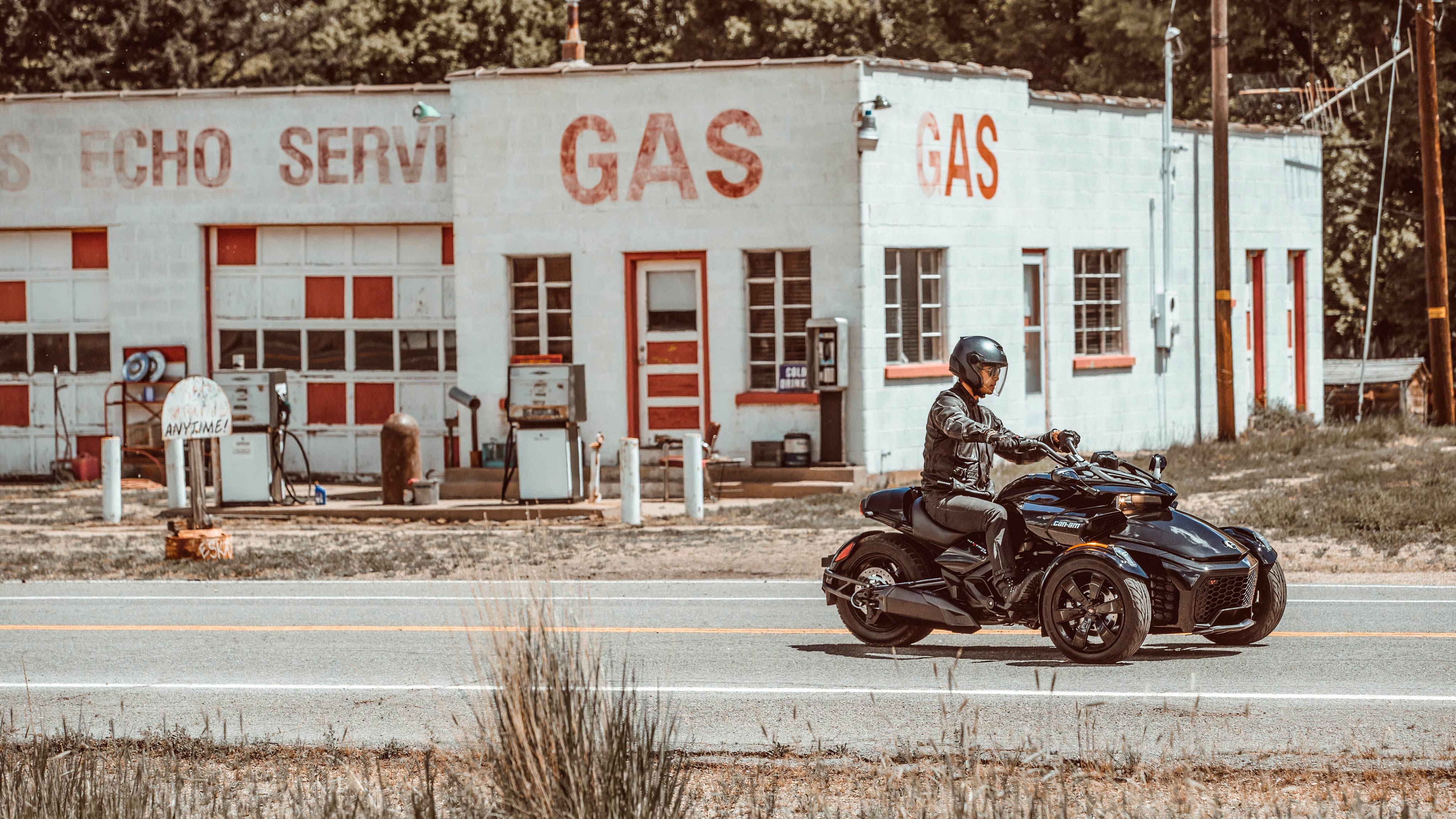 Man driving his Spyder F3 past a gas station