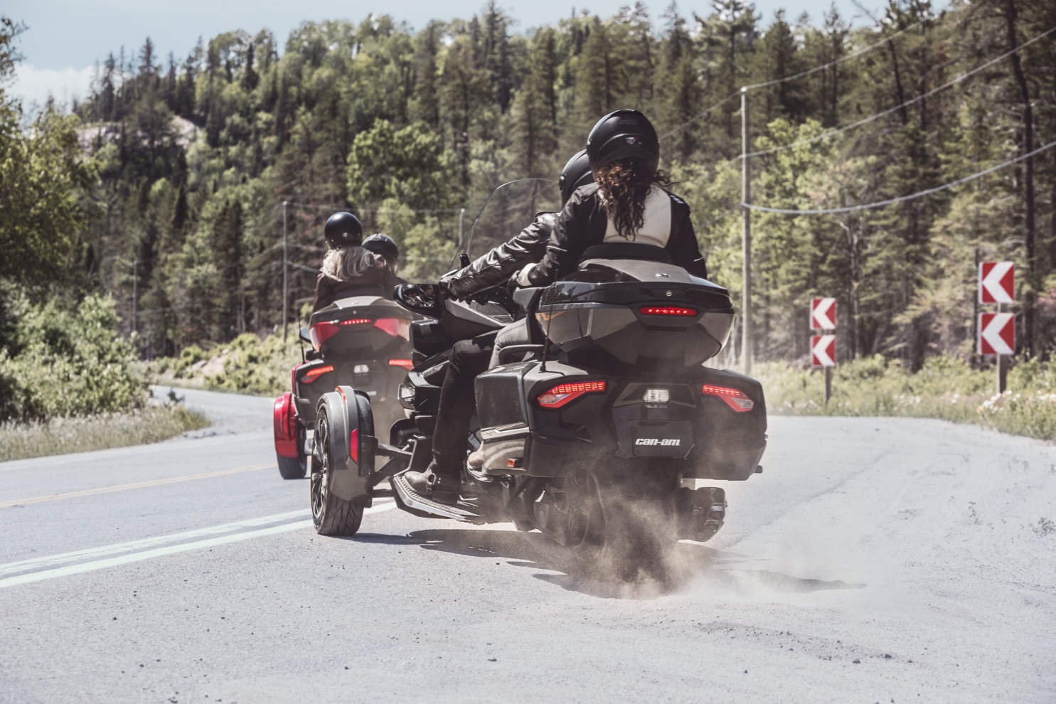 Rear ended view of two couples driving their Spyder RT on a road 
