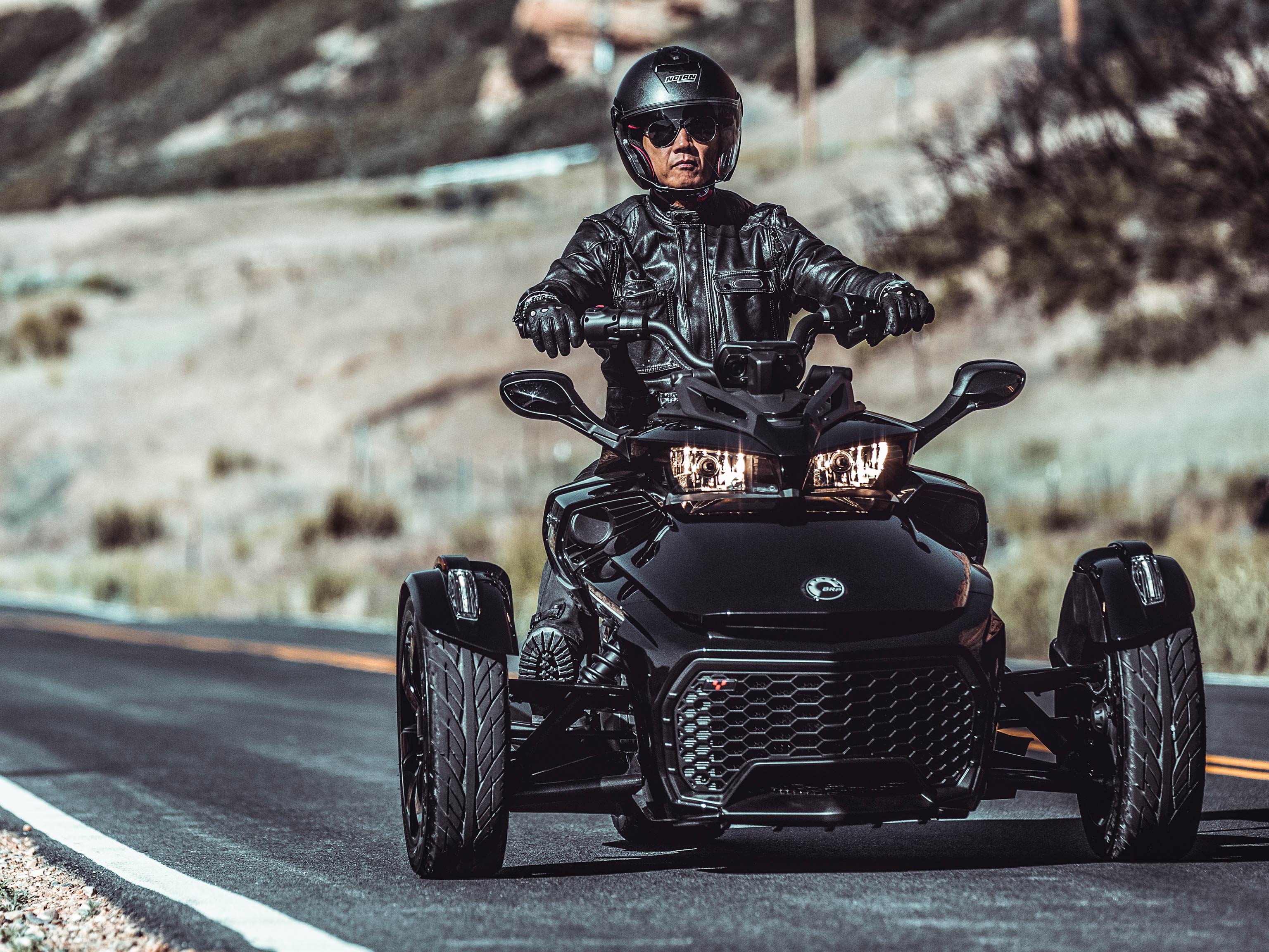 Moški vozi njegov Can-Am Spyder po prazni cesti v puščavi