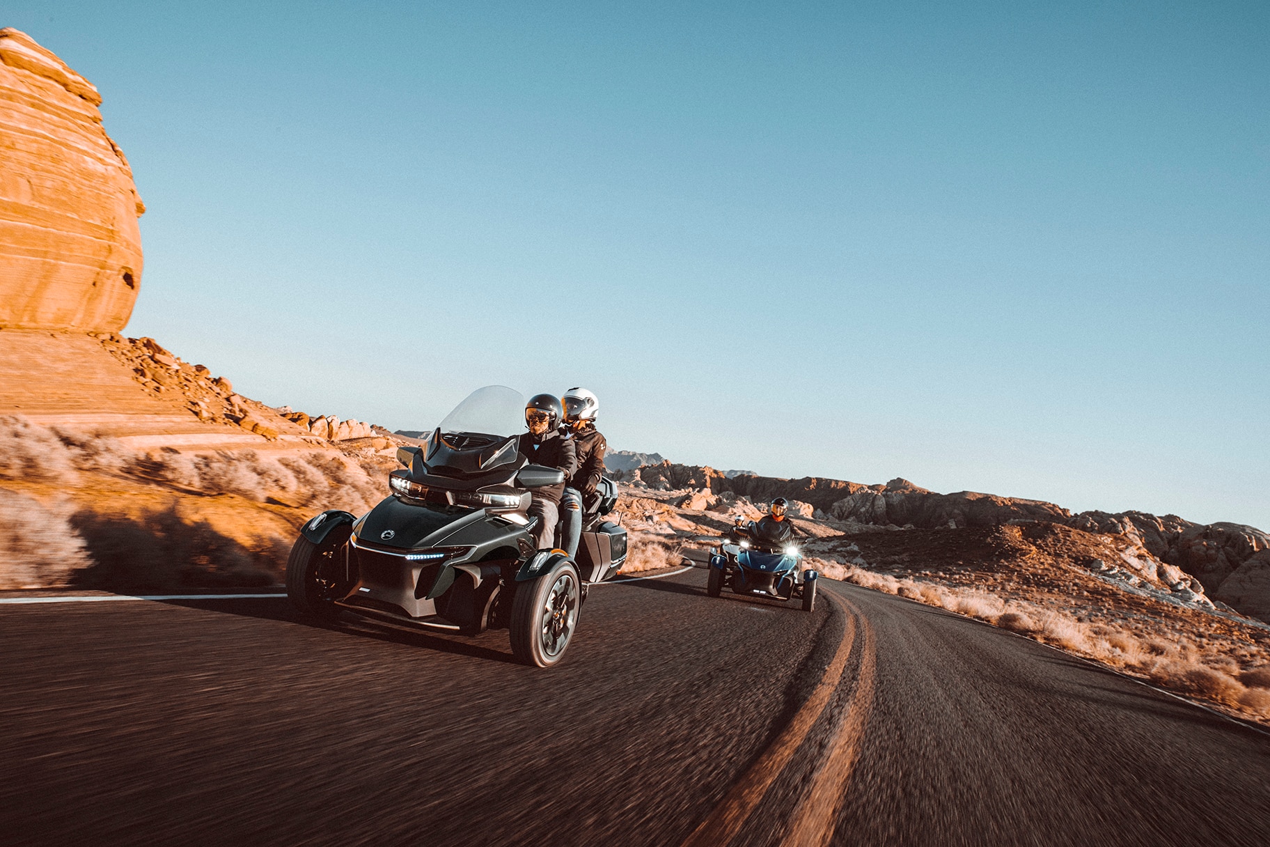 Un couple conduit leur Spyder RT dans la rue