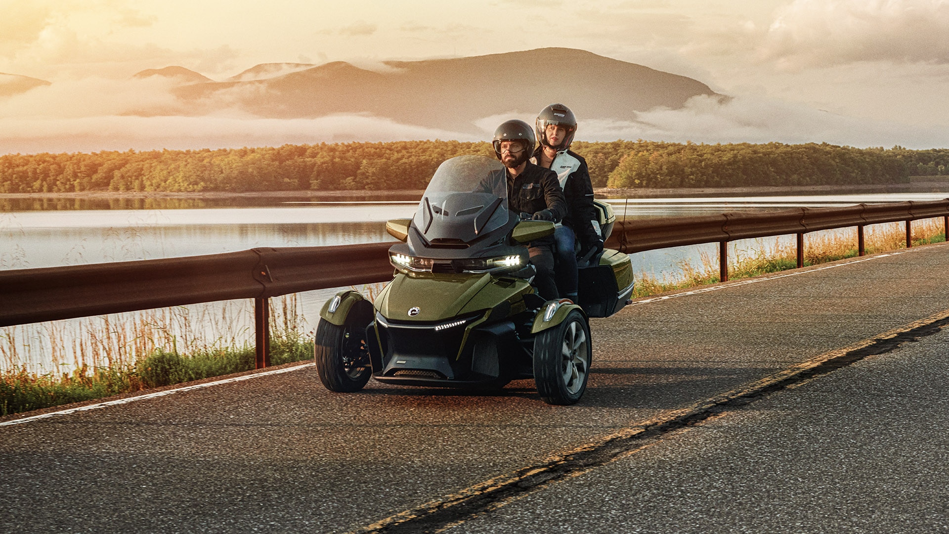 A man and a woman riding Can-Am Spyder 2021 near the lake