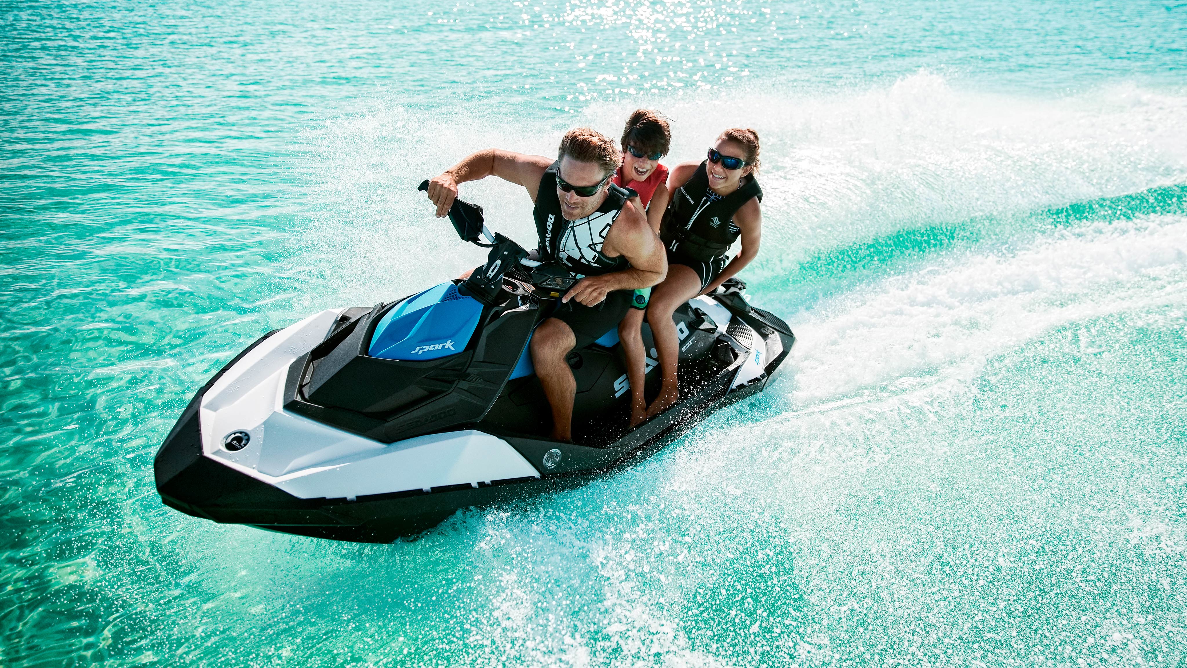 A family rides a Sea-Doo Spark in clear blue water