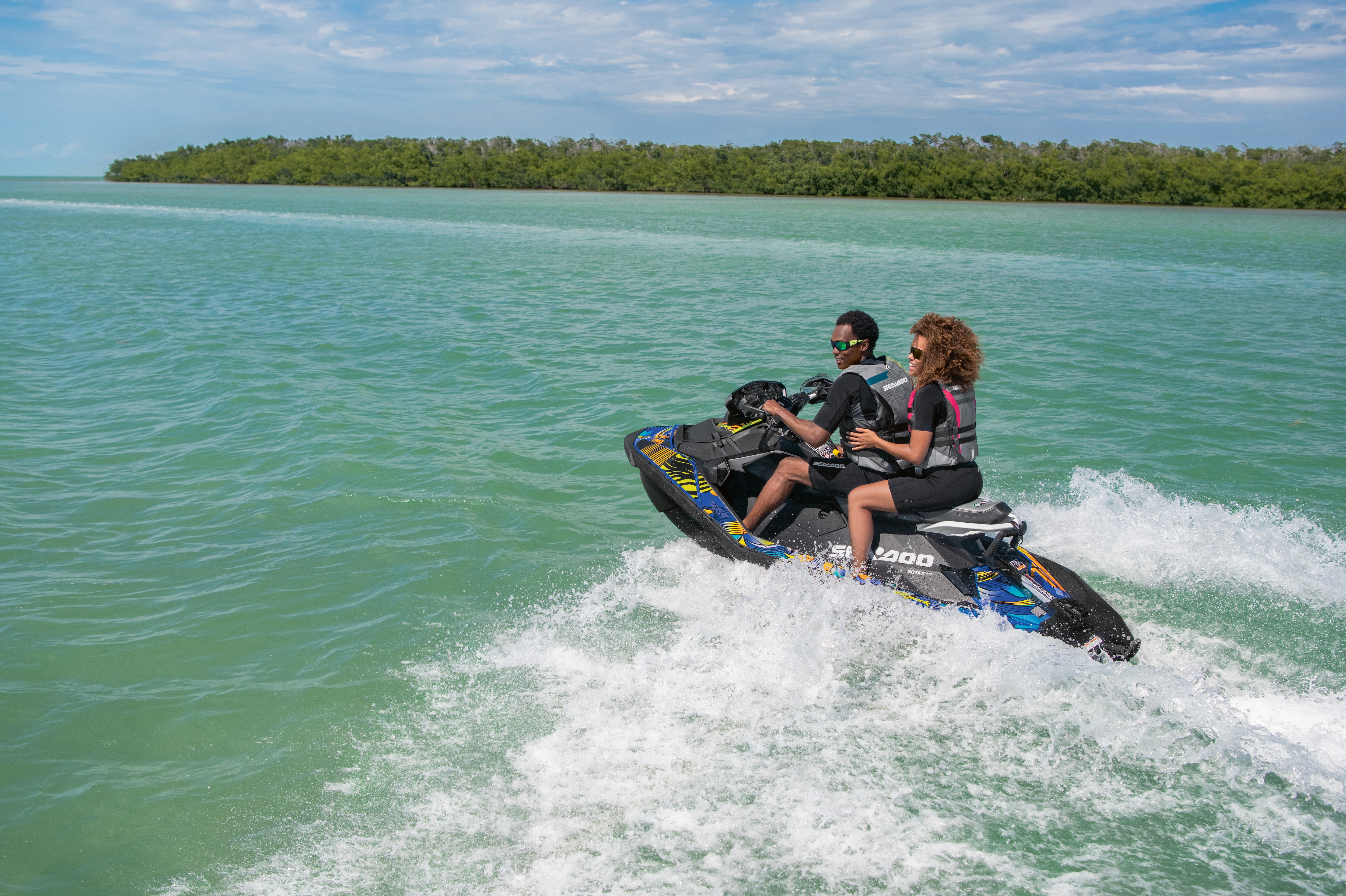 Rear view of a couple riding their Sea-Doo Spark water near a patch of land