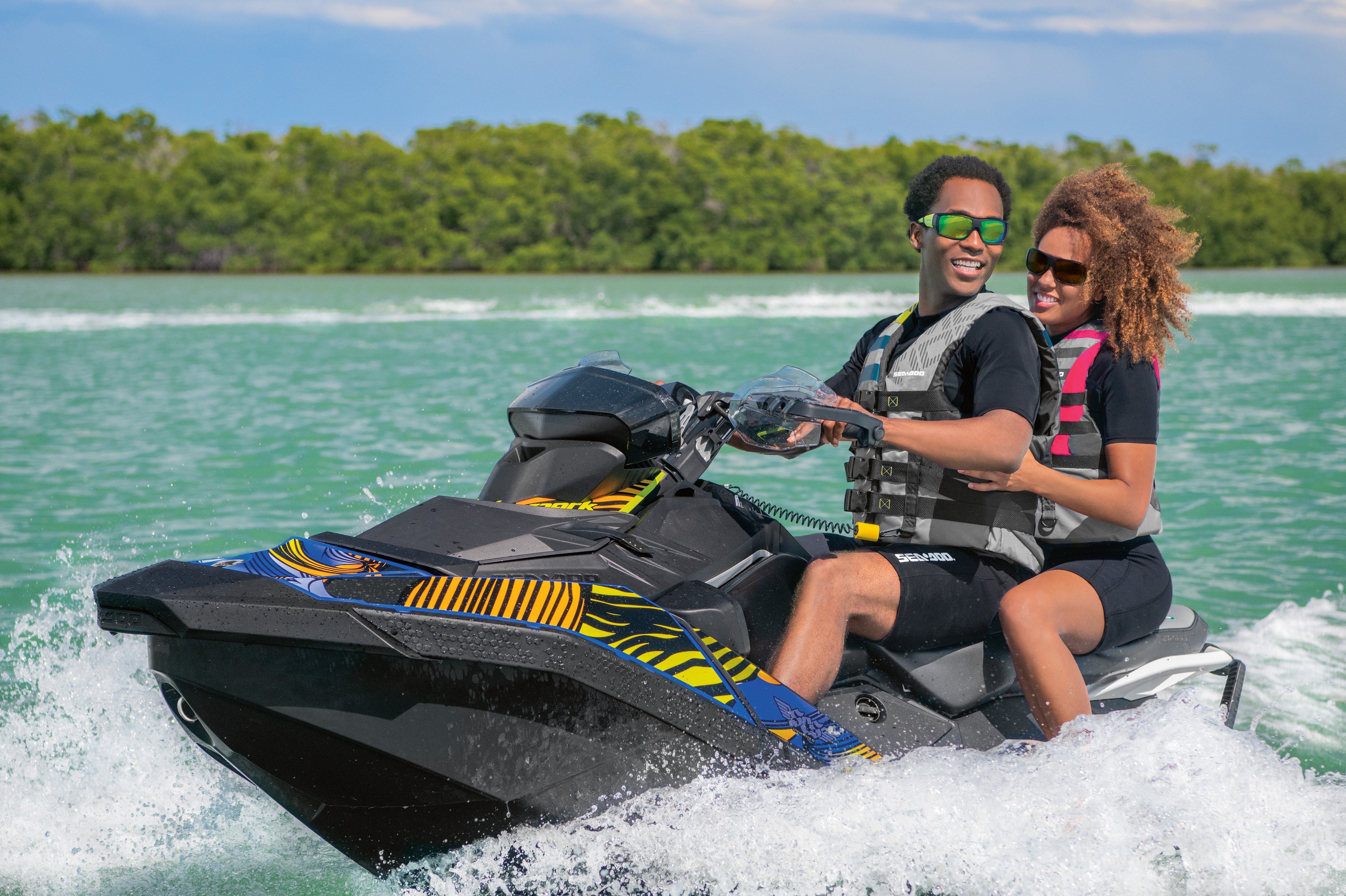 Close-up of a couple riding their Sea-Doo Spark water near a patch of land