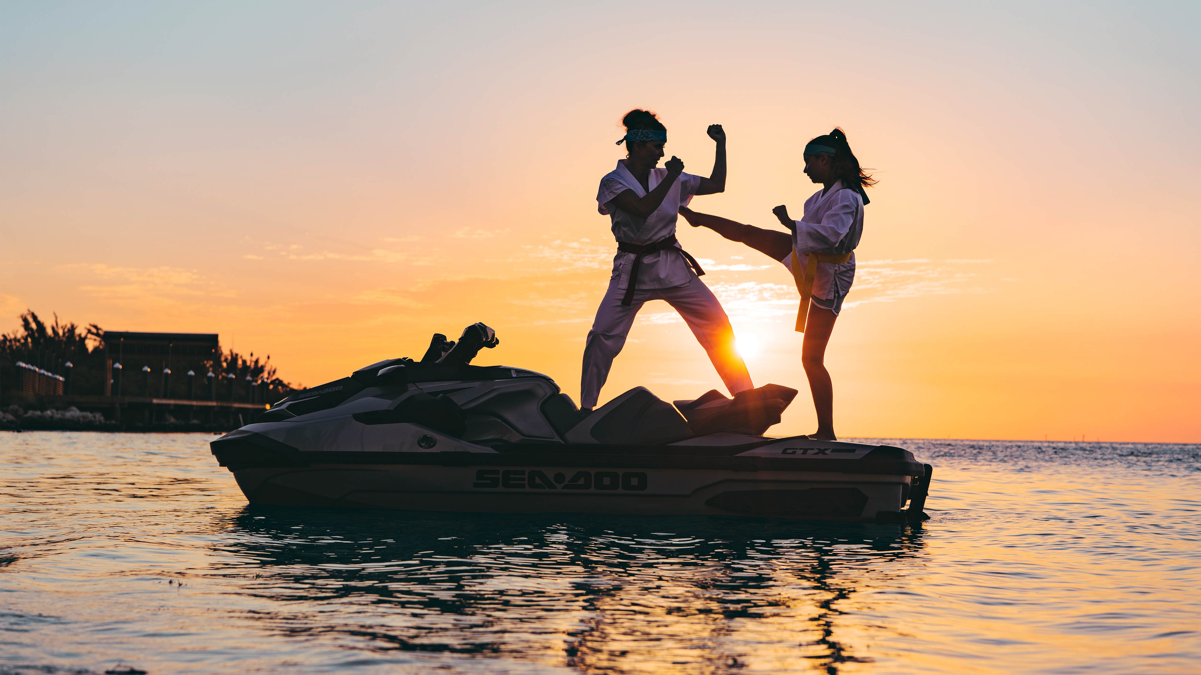 Two women doing karate while standing up on a Sea-Doo GTX Limited