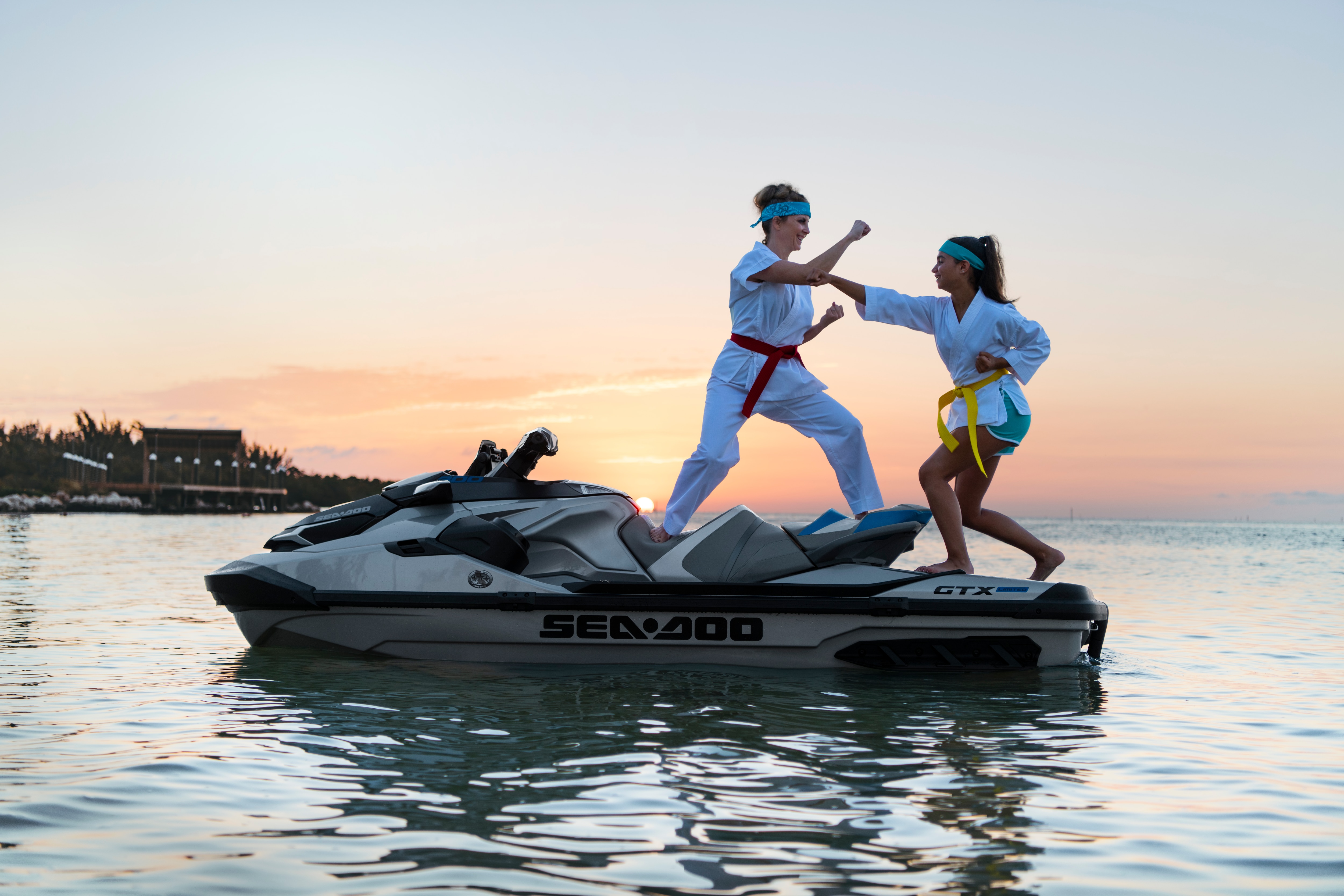 Two women doing karate while standing up on a Sea-Doo GTX Limited