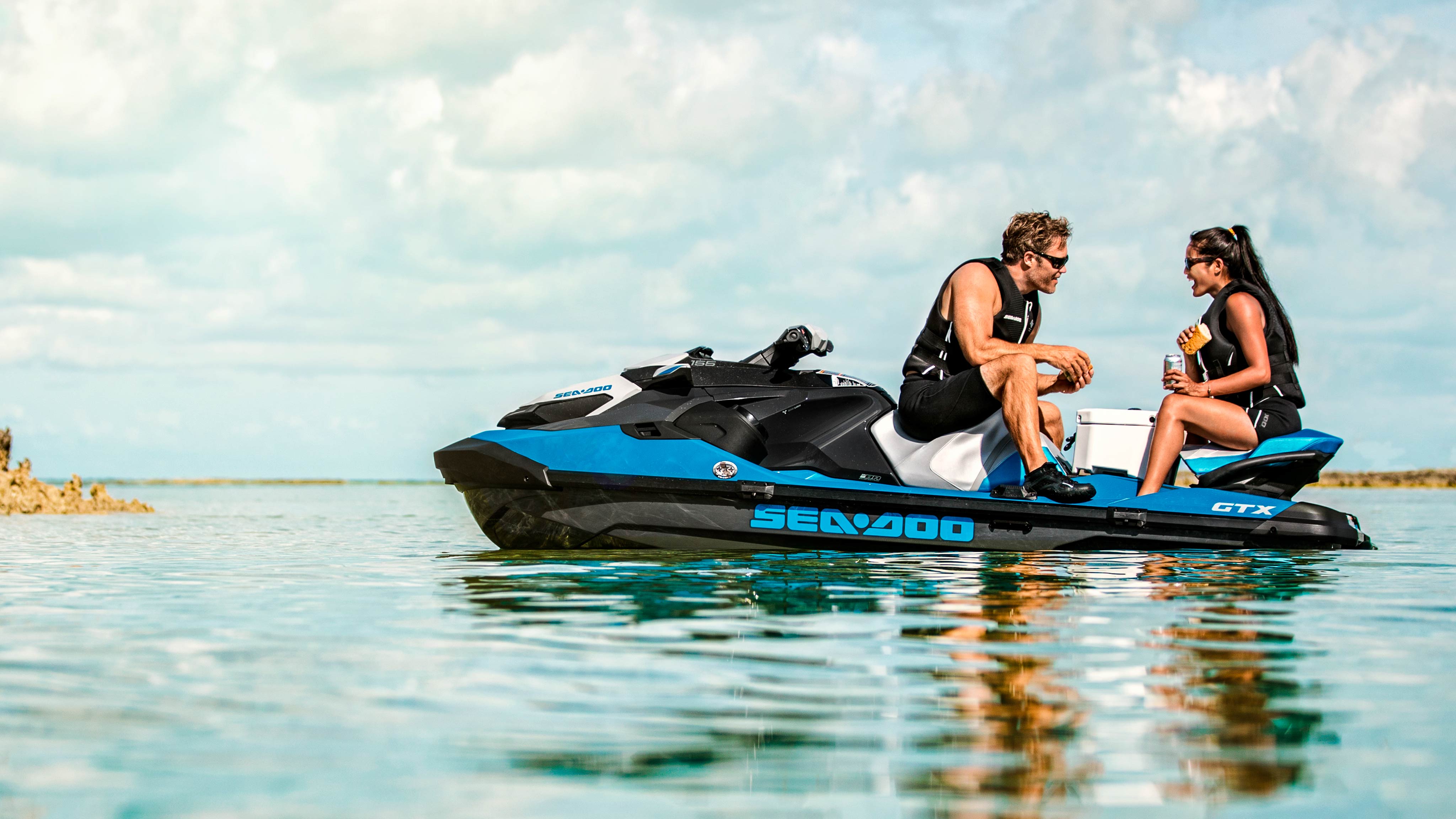 Wide angle shot of a man and woman talking on a Sea-Doo GTX