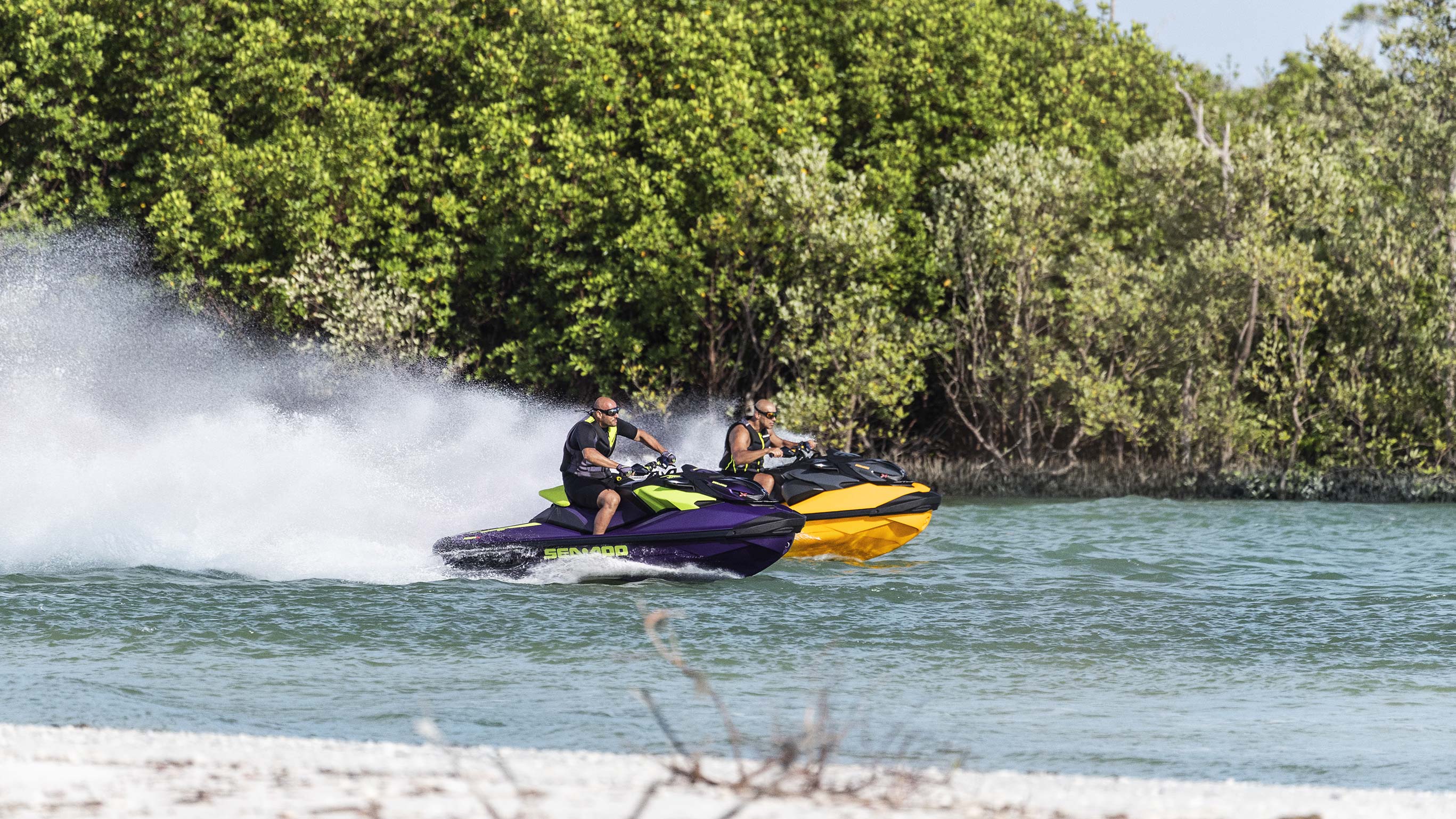 Two men riding Sea-Doo watercrafts very fast