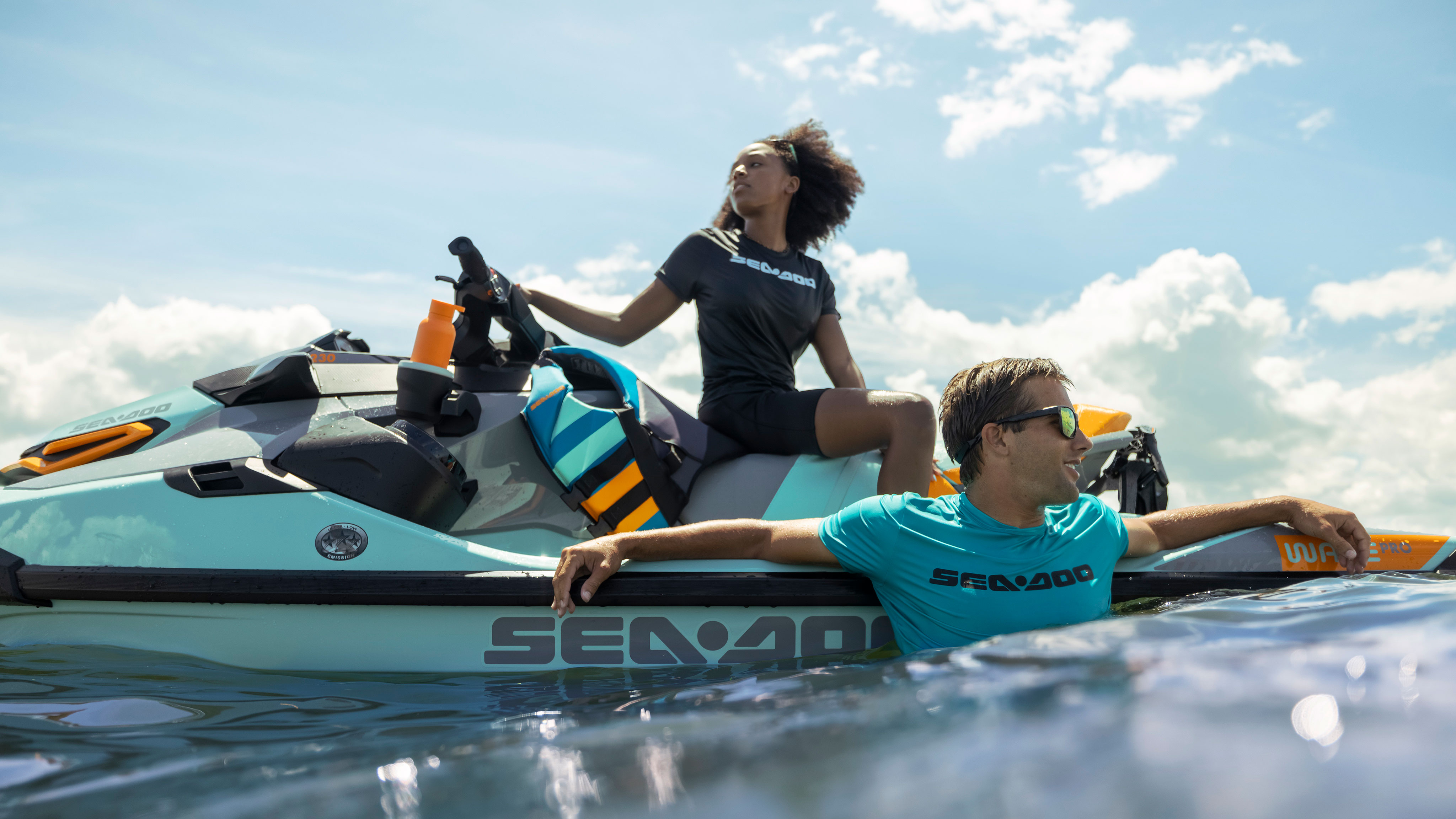 Sea-Doo Wake Pro'da oturan ve yanında yüzen bir adamla kadın